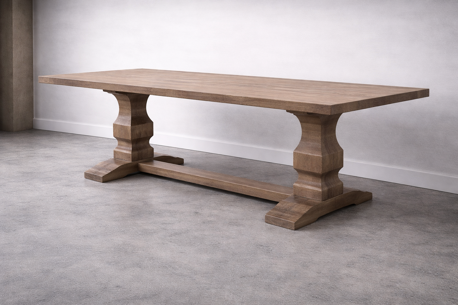 A wooden dining table with large, sculpted pedestal bases on a light gray carpeted floor, against a white wall.
