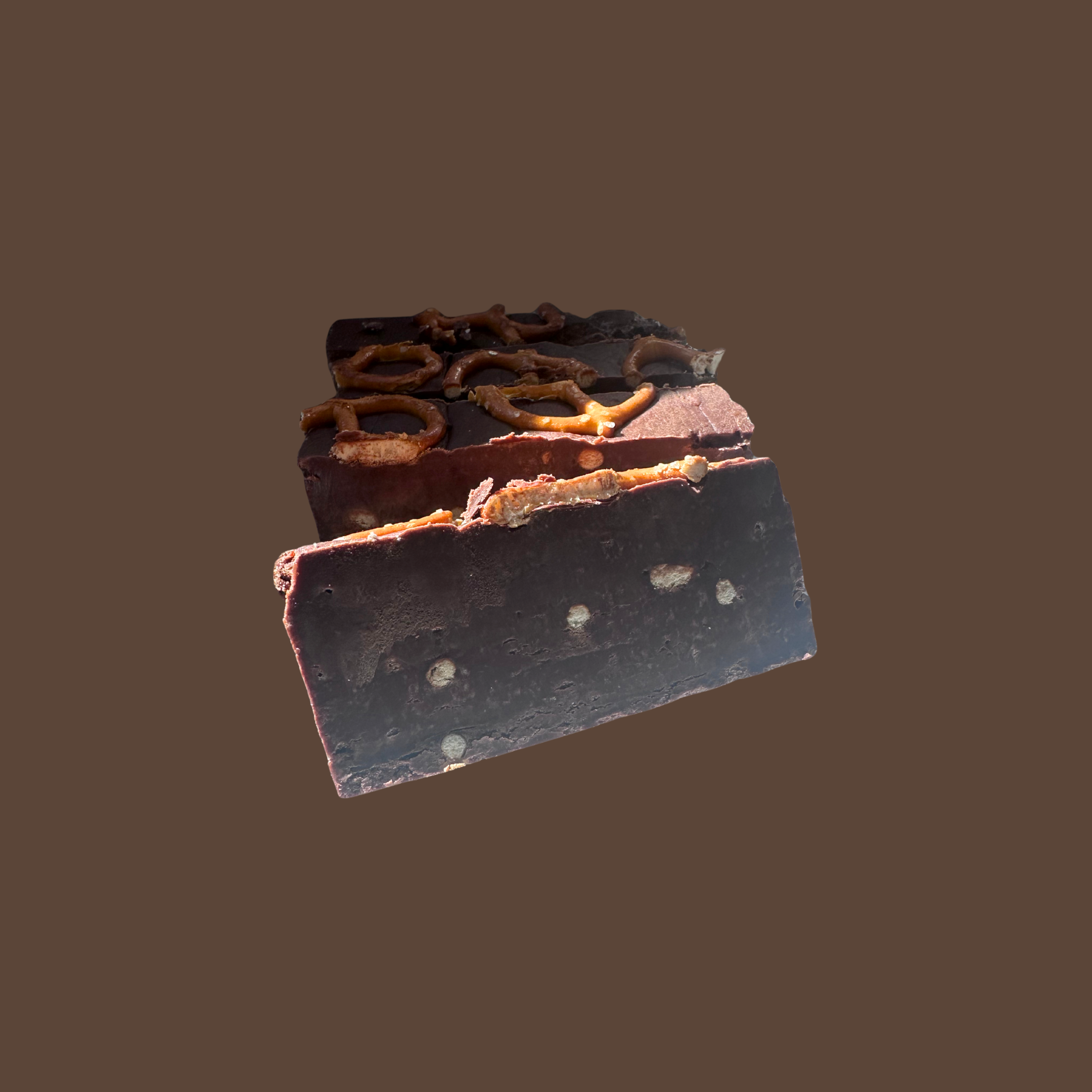Close-up of a chocolate bar with pretzels on top against a plain background.