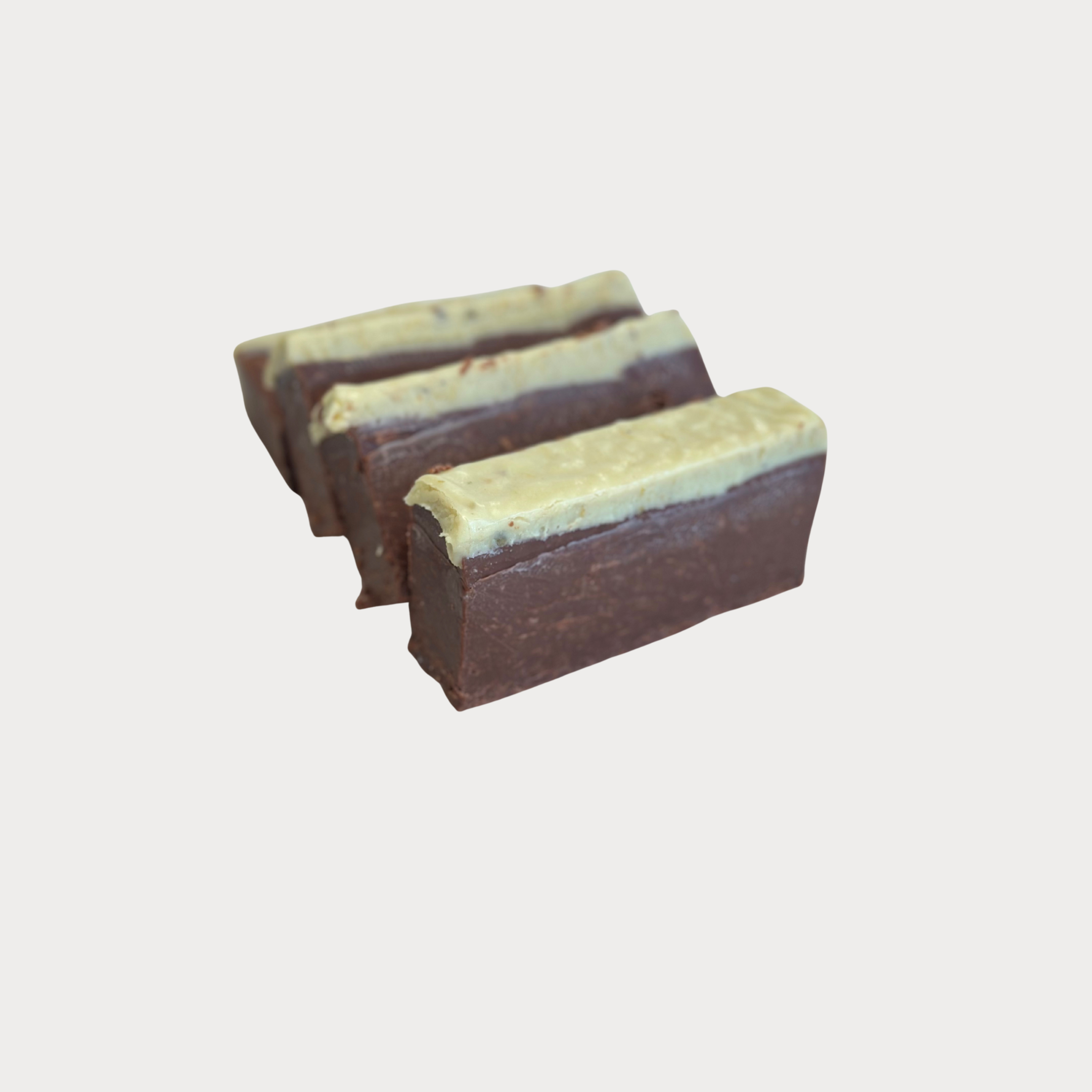 Three pieces of layered chocolate and vanilla fudge arranged diagonally on a plain white background.