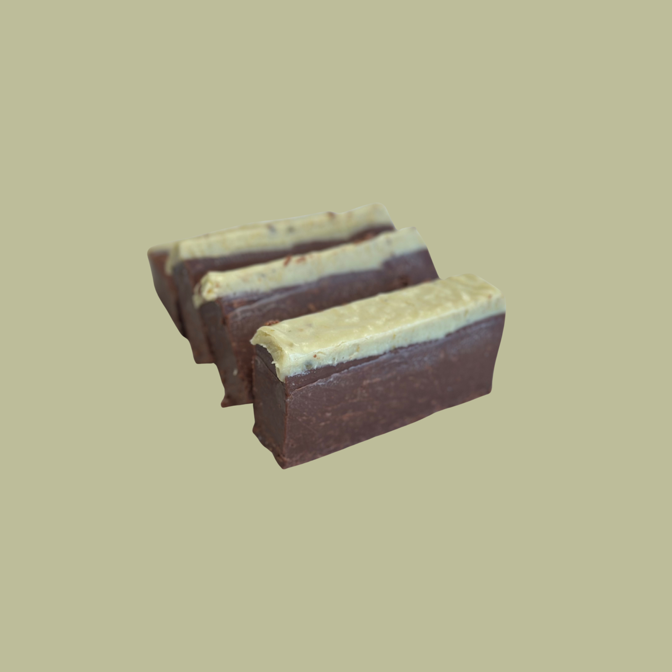 Three pieces of chocolate fudge with a pistachio topping on a plain background.