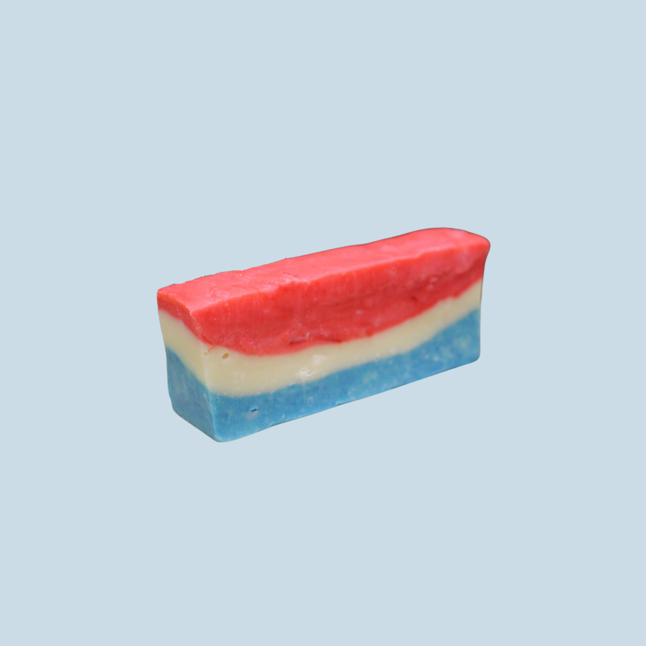 A bar of layered fudge with red, white, and blue on a light blue background.
