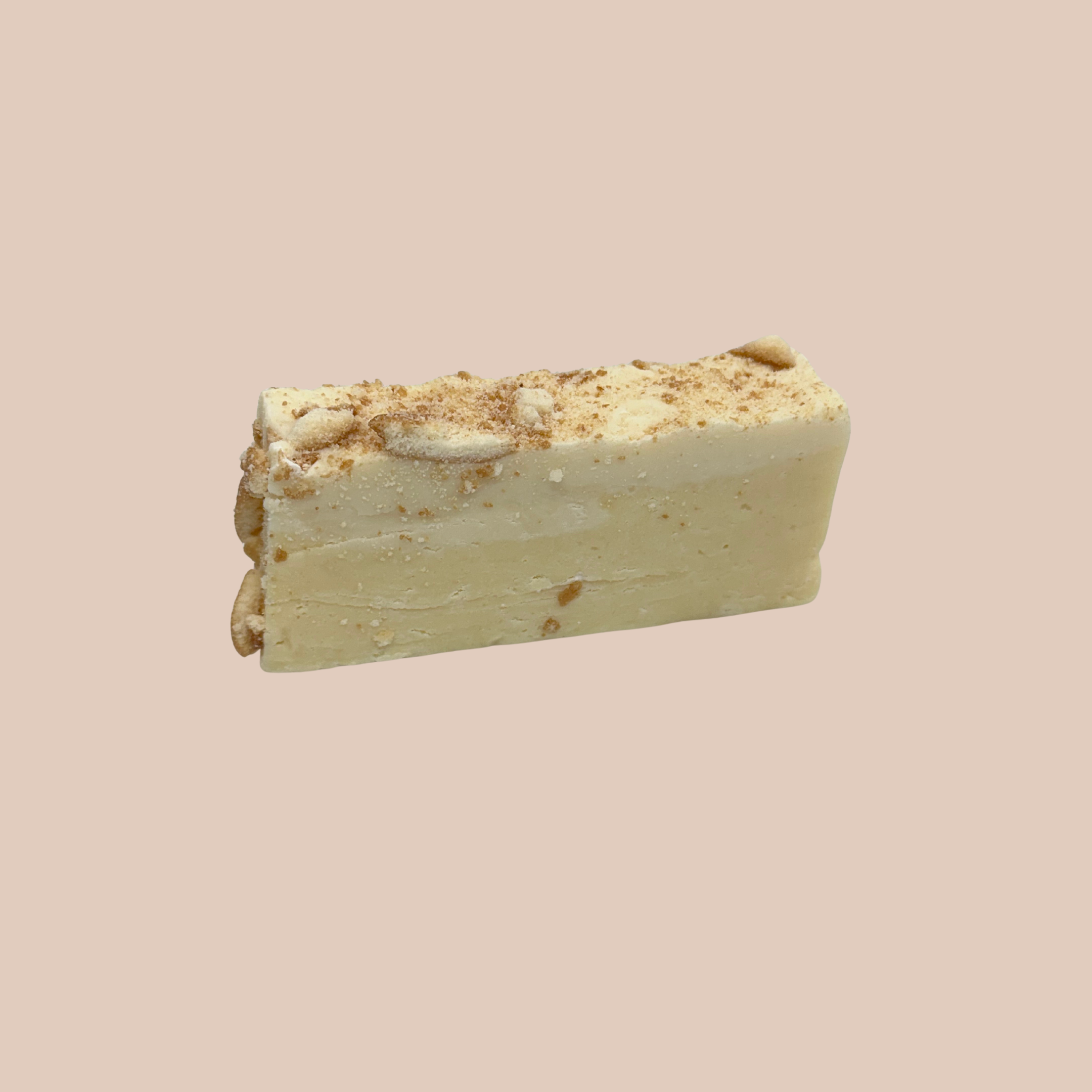 A bar of white chocolate with a crumb topping on a light pink background.