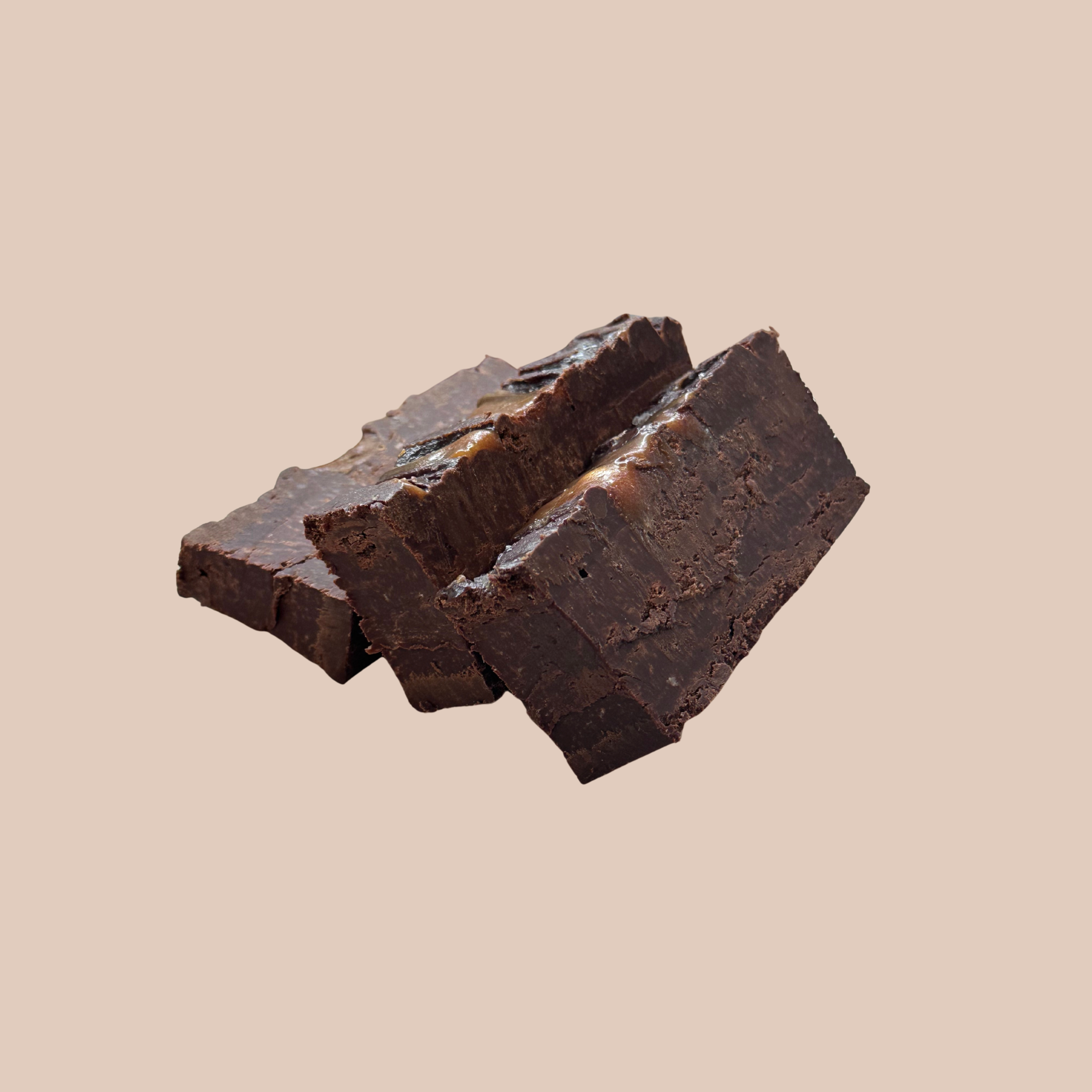 Two pieces of dark chocolate fudge on a beige background.