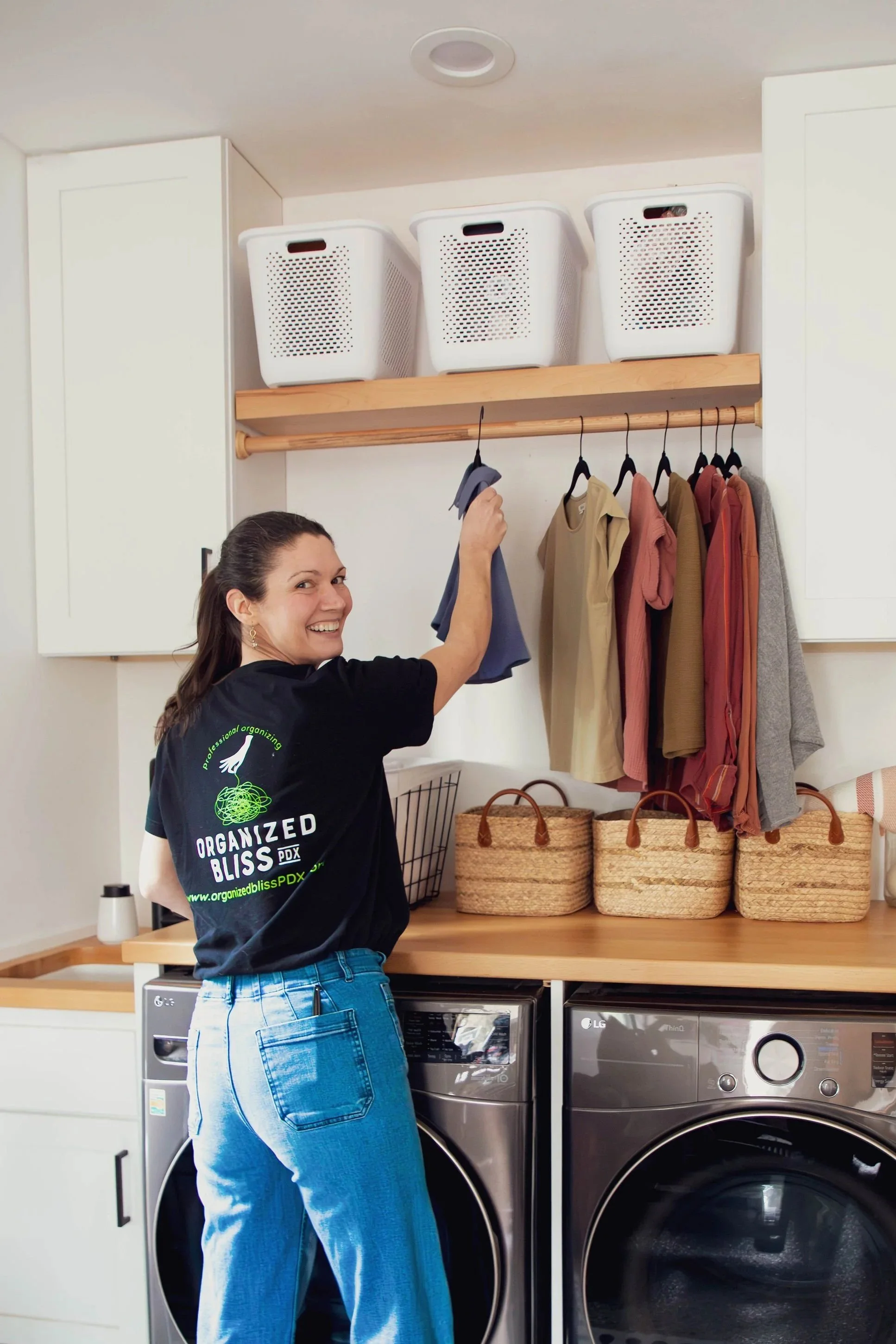 Person folding and organizing a stack of folded clothes on the floor.