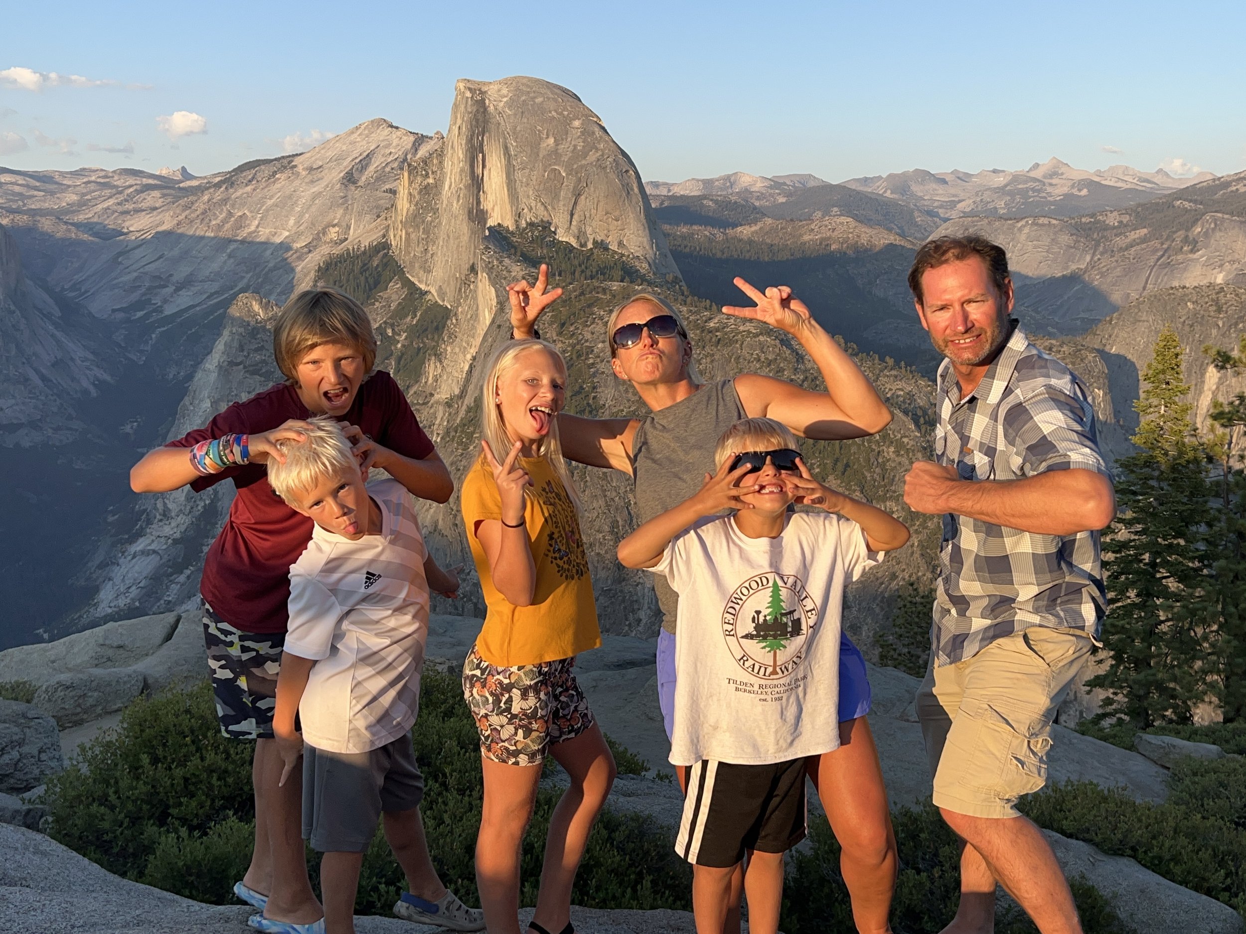 Family group taking a selfie with the Half Dome mountain in Yosemite National Park in the background.