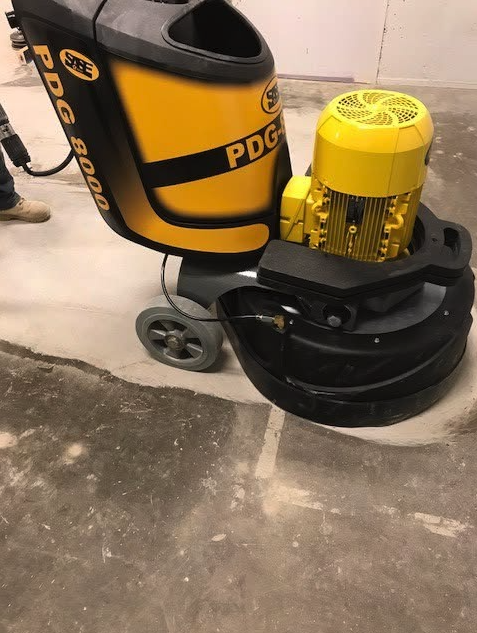 Yellow and black industrial floor grinding machine with a large yellow motor, labeled PDG 800, on a concrete floor.
