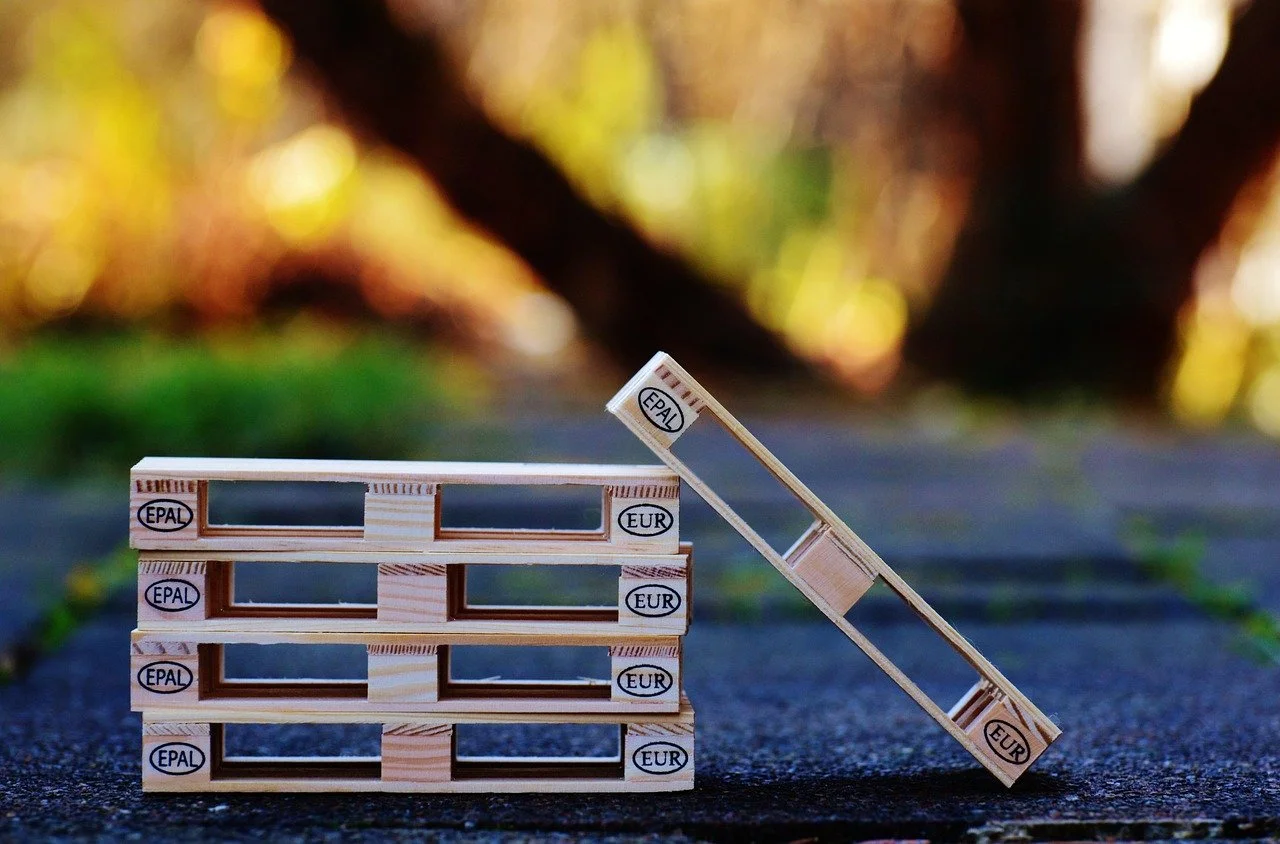 Tre pedane di legno e una rampa in miniatura, usate per giocare o come decorazione, con scritte 'EPAL' e 'EUR' su di esse, posizionate sulla strada.