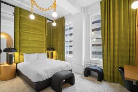 Modern bedroom with white bed, green accent walls, large windows with yellow curtains, and minimalist furniture.