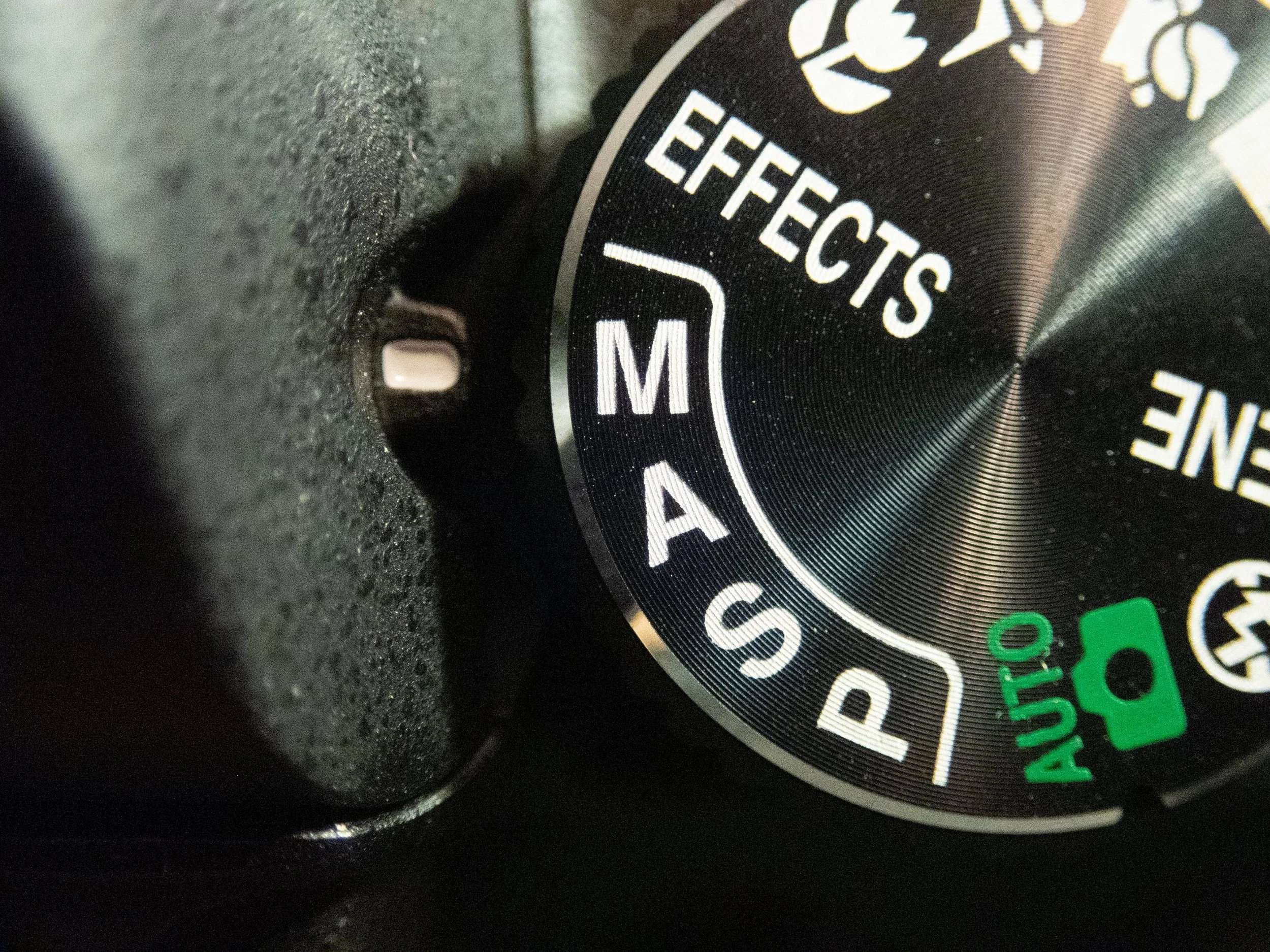 Camera mode dial showing settings like 'AUTO' and 'Effects' with a small part of the camera body visible.