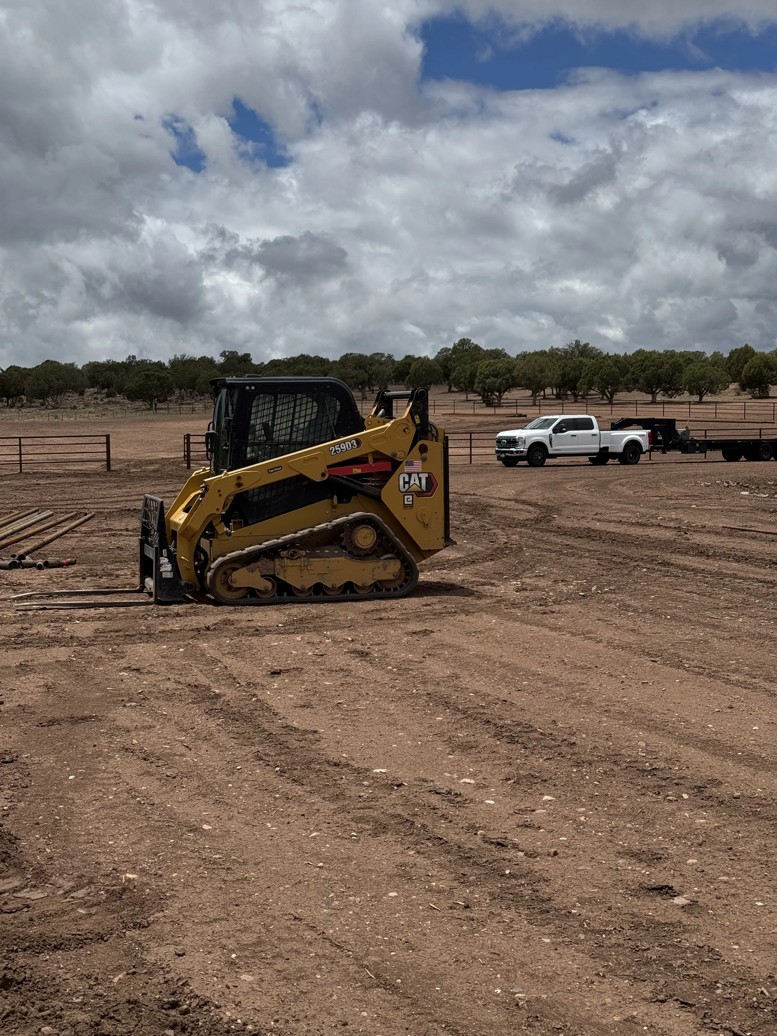 A Cat skid steer on a dirt construction site with our four rail 2 7/8 pipe top rail and 1 7/8'' rails.