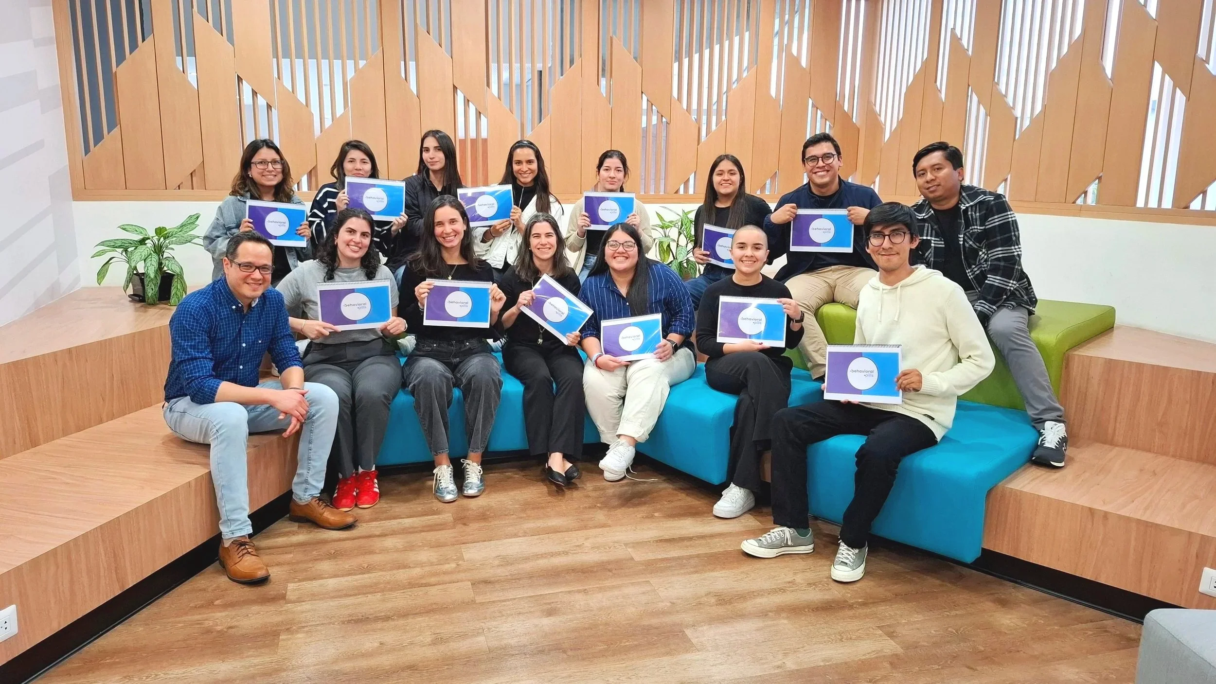Grupo de jóvenes en una sala moderna, algunos sosteniendo certificados, todos sonriendo y posando para la foto.