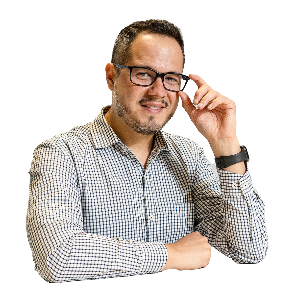 Hombre con gafas ajustándoselas, vestido con camisa de cuadros, luciendo una expresión confiada y sonriendo ligeramente.