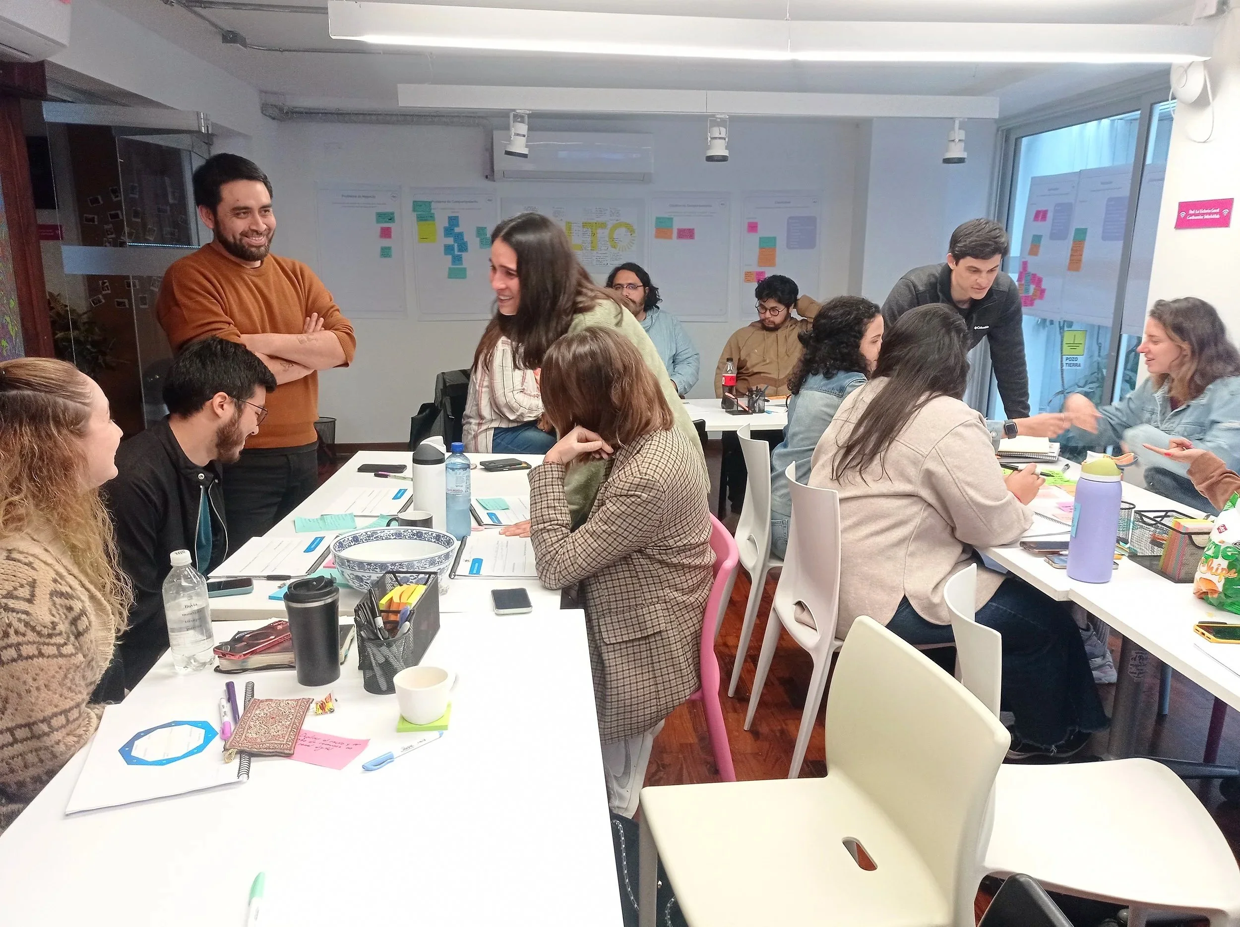 Grupo de personas en una sala de reuniones participando en una discusión o taller, con materiales de oficina y papeles en la mesa.