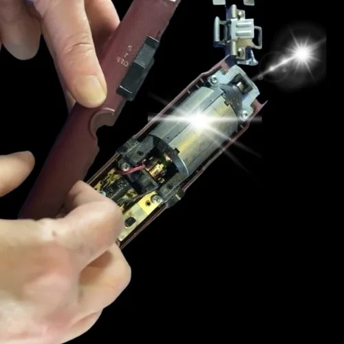 A person holding a disassembled electronic device with visible internal components, including a motor and circuit board.