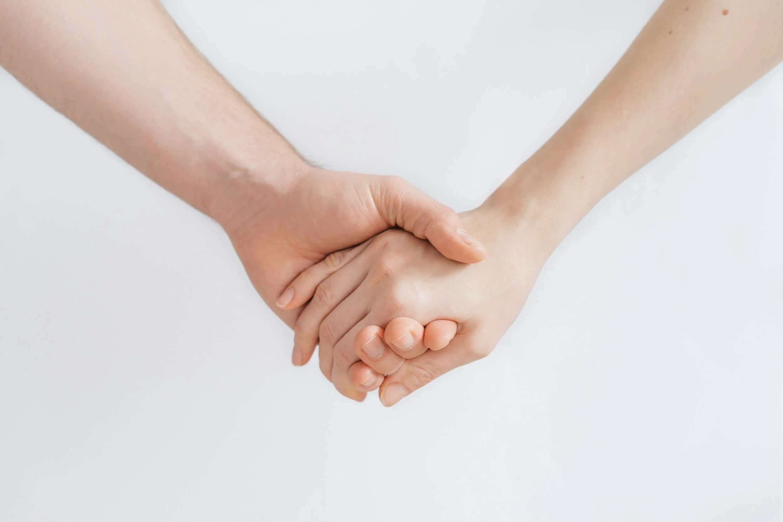 Two people holding hands against a plain white background.