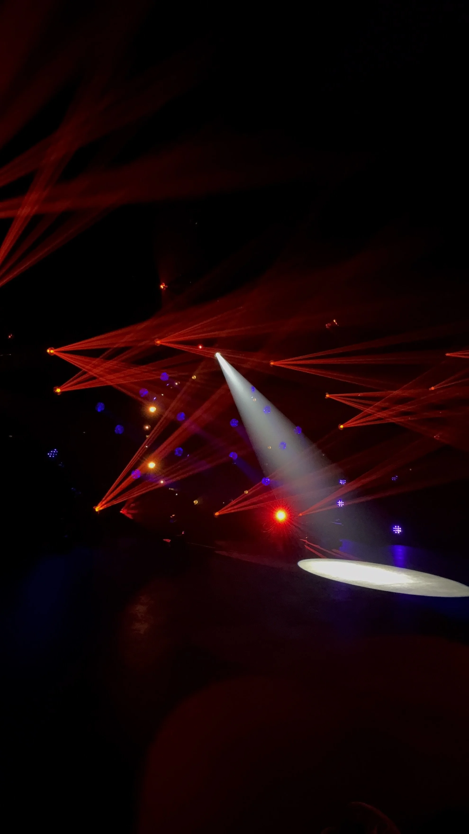 Cinematic stage lighting by EchoLight using dramatic red beams and a sharp white spotlight to shape emotions and atmosphere at a high-end event.