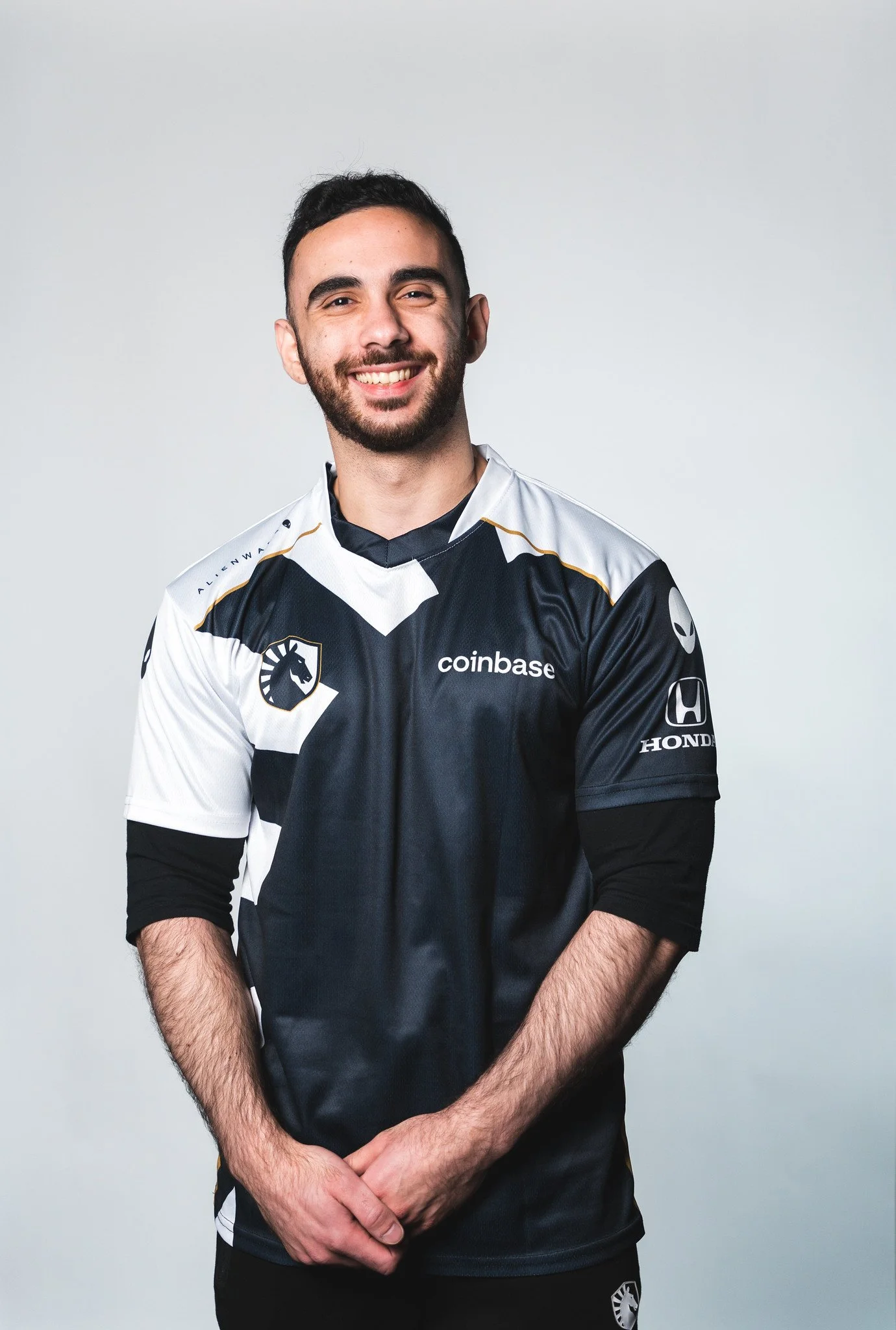 A young man smiling while wearing a black and white esports team jersey.