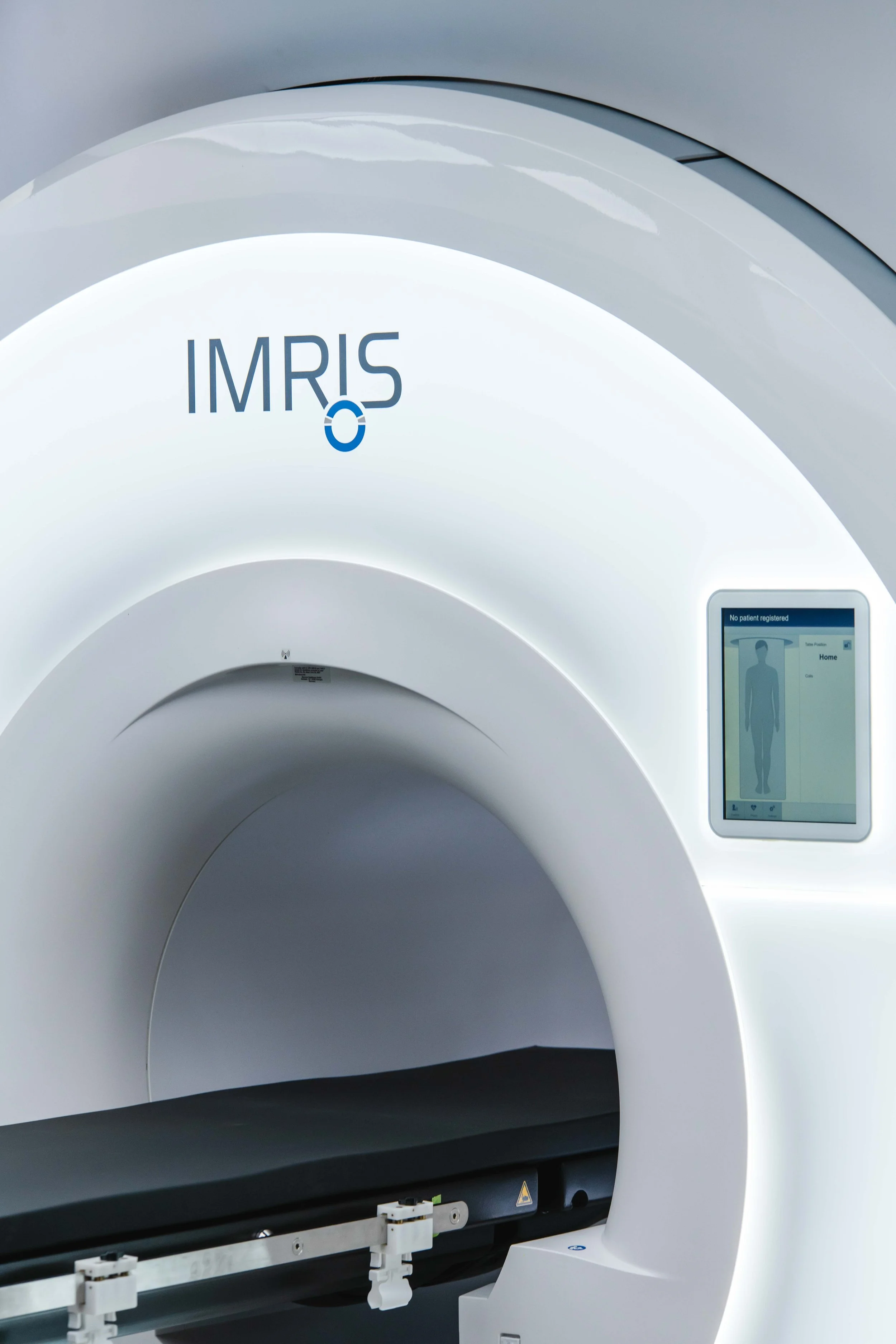 A modern medical MRI machine with a white exterior and a digital display panel on the side.