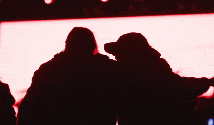 Silhouettes of two people enjoying a music festival together.