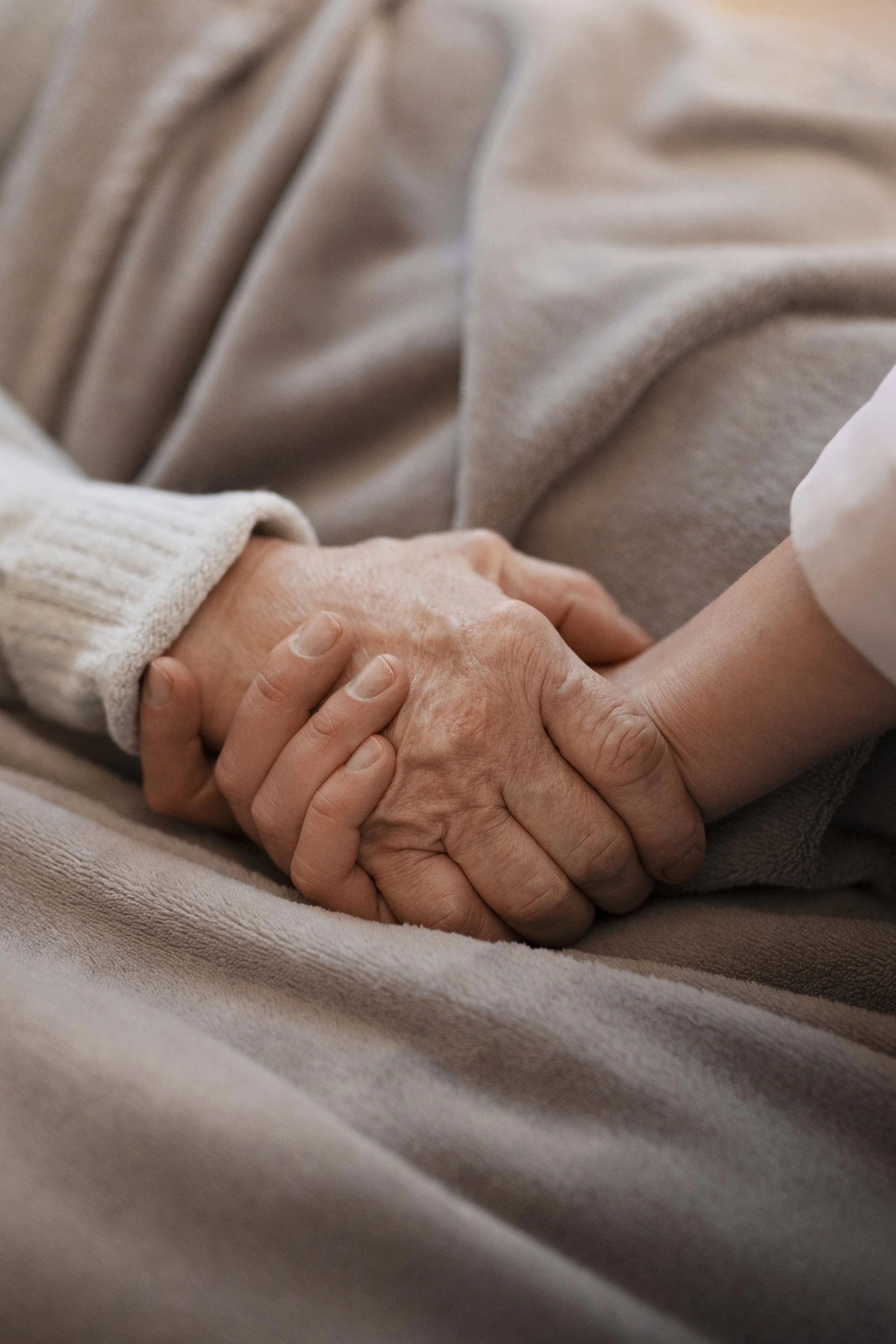 Patient and family member holding hands, symbolizing supportive palliative care and family-centered treatment.