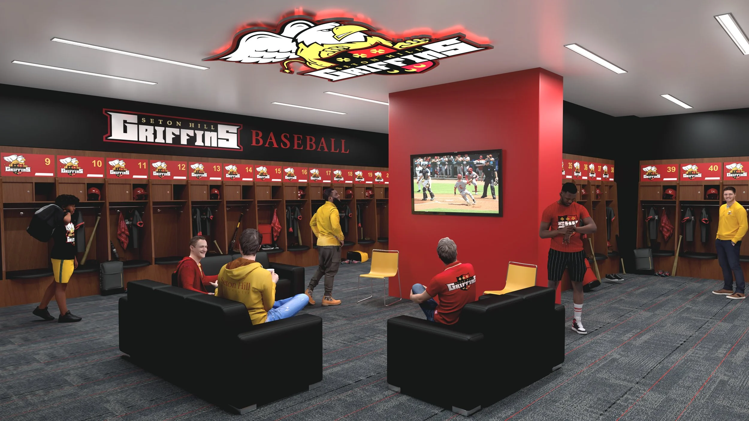 Inside a baseball team locker room for the Seton Hill Griffins, with lockers numbered 9 to 40, helmets, and gear. Several players and staff are relaxing, some watching a game on a large television, and others preparing or standing around.