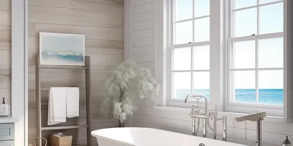 A bright bathroom with large windows overlooking the ocean, a white bathtub, and a ladder-style towel rack with towels.