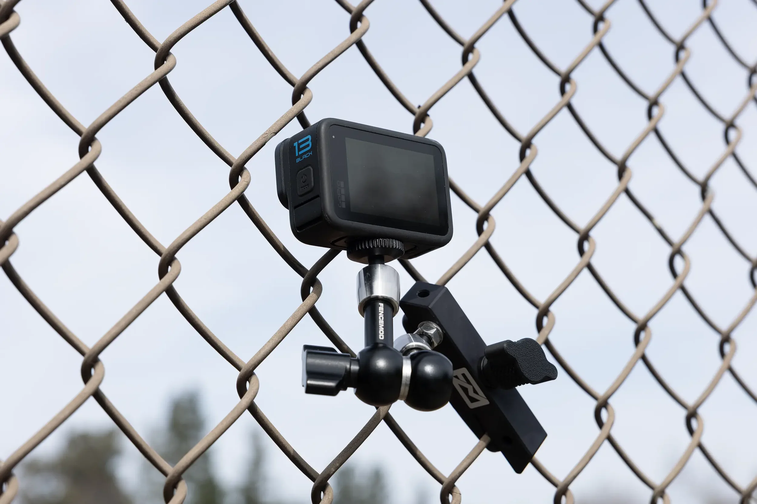 A digital GoPro camera mounted on a chain-link fence using the FM Core clamp by Fence Mod.