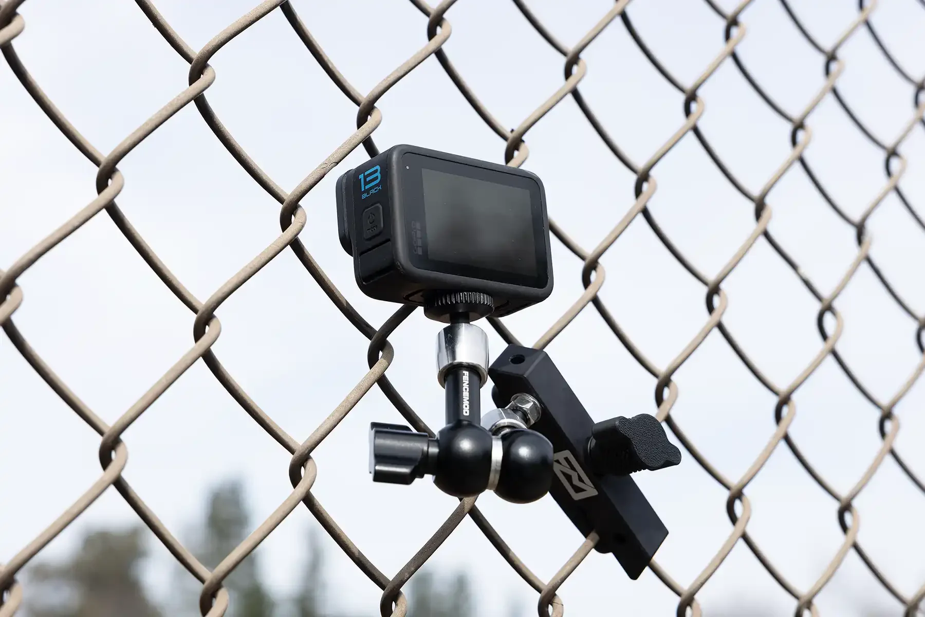 This image depicts a GoPro Hero Black 13 mounted on a fence using a Fence Mod Chain Link Fence Camera Mount.