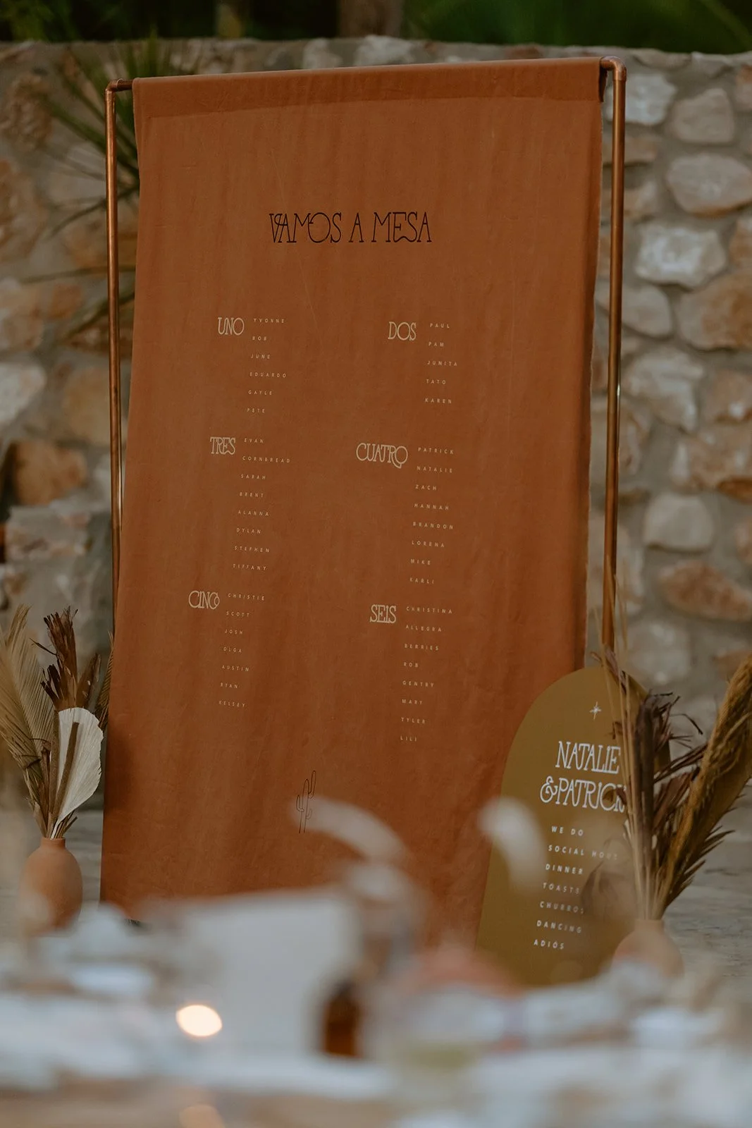 Table seating chart with names listed under numbered sections, with a decorative sign in the bottom right corner that reads 'Natalie & Patrick.'