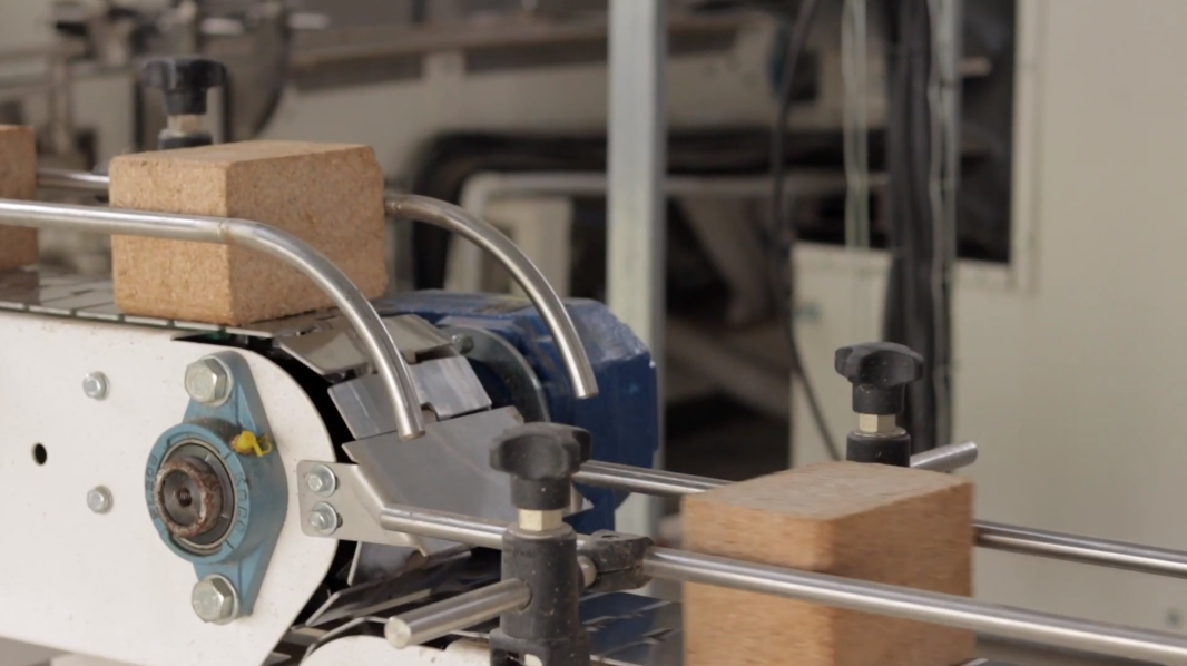 A machine sorting bricks on a conveyor belt in a factory or workshop.