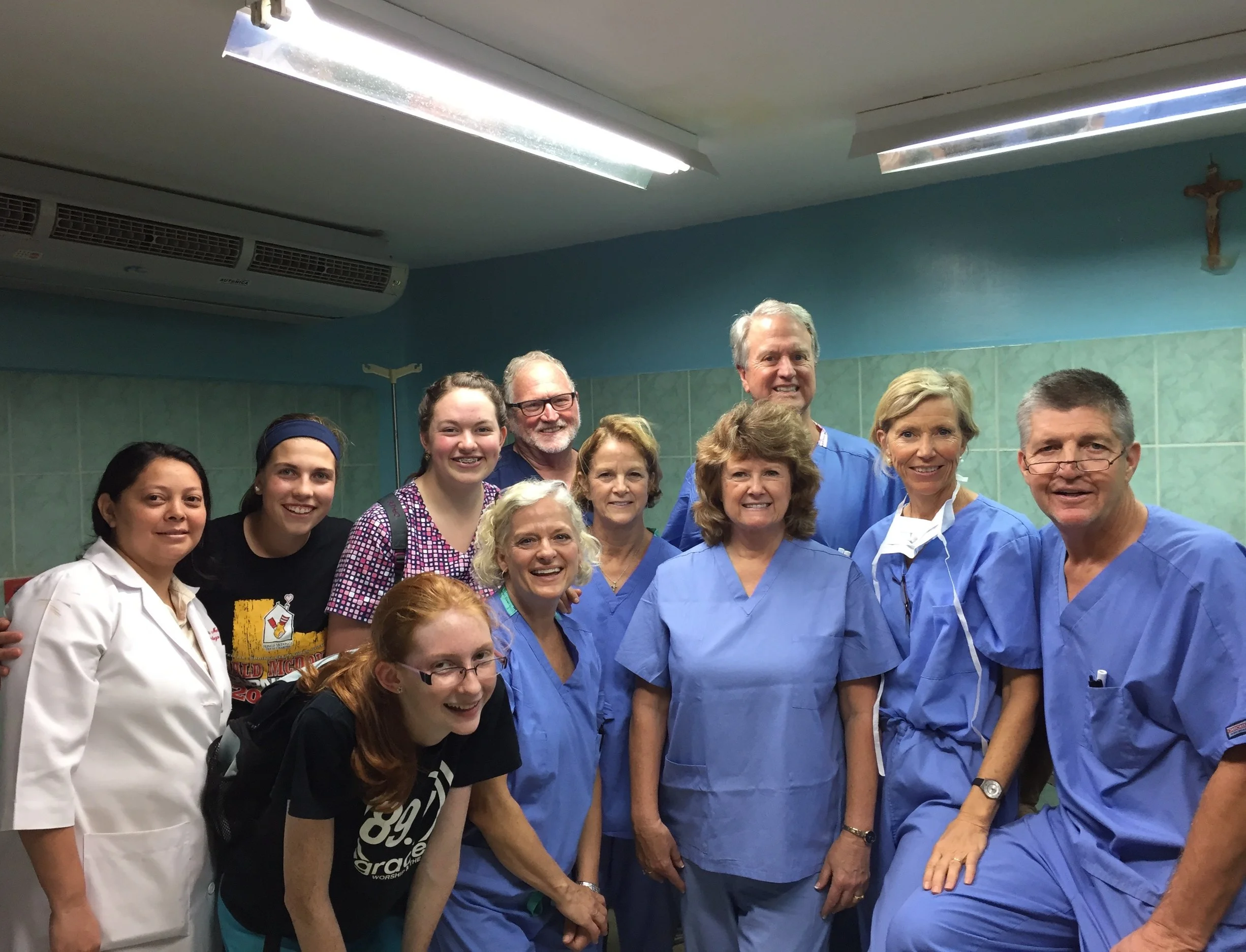 Group of healthcare workers, including nurses and doctors, smiling in a hospital or clinic setting.