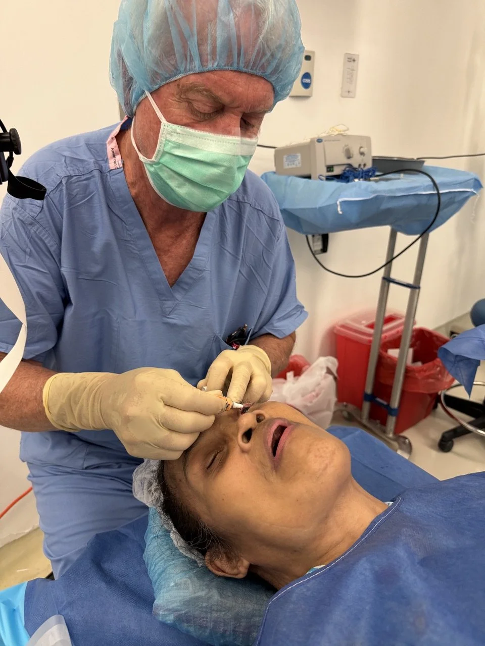 Medical professional giving an injection to an older woman in a hospital setting.