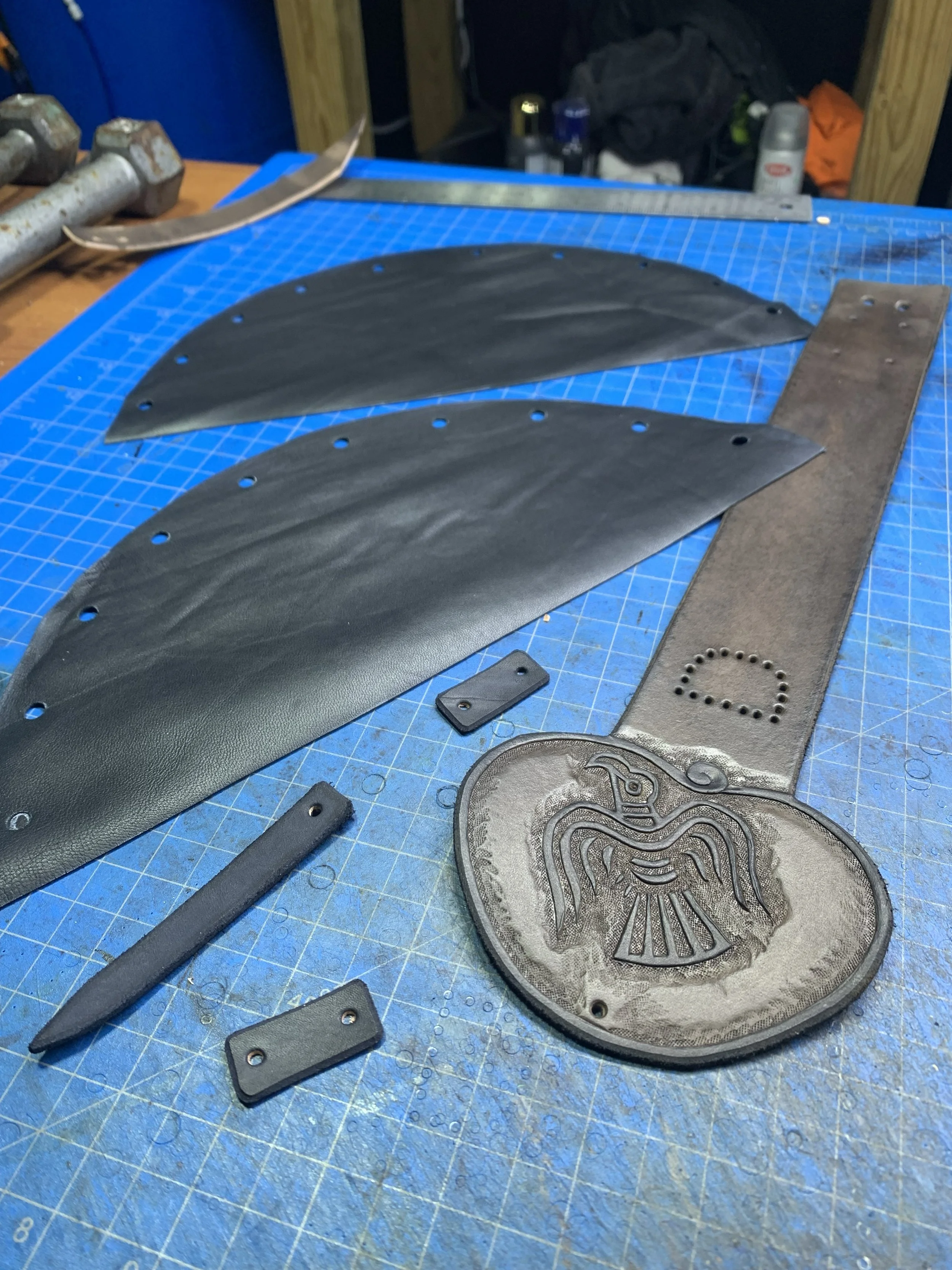 Black leather pieces, cut, carved, and ready for assembly into a bag.