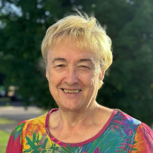 Smiling woman outdoors with blurred trees in the background