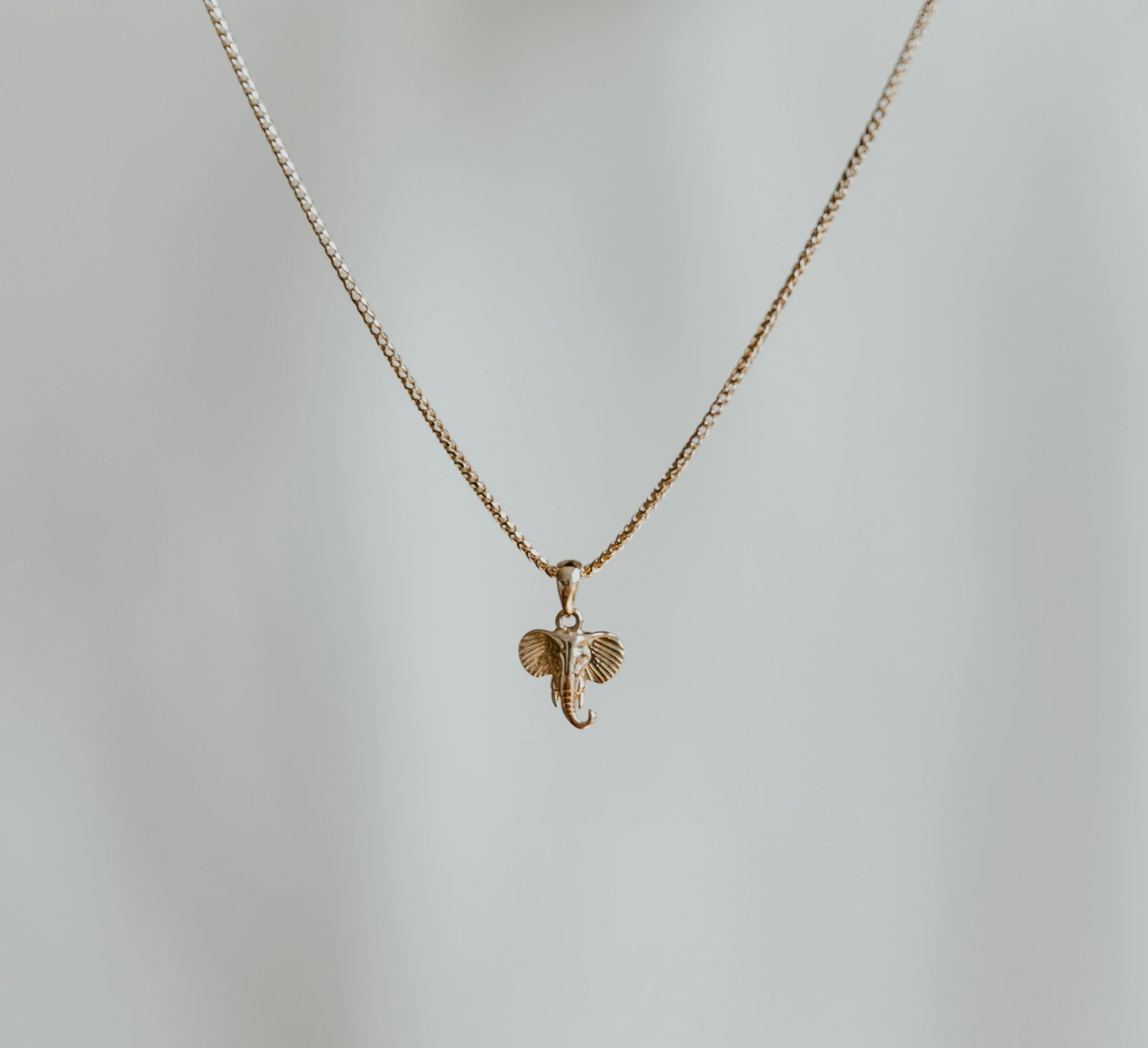 Close-up newborn photography highlighting a keepsake necklace given to the baby, perfectly preserved in the image.