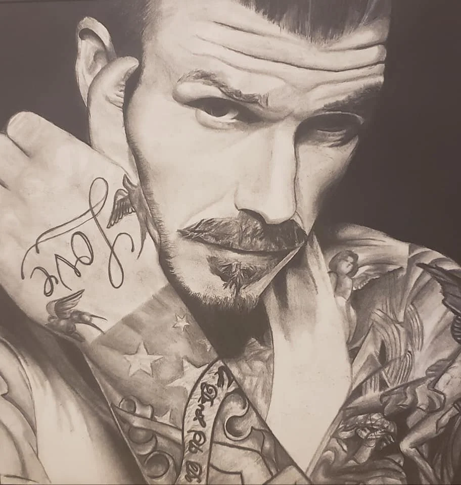 Black and white portrait of a bearded man with tattoos, resting his head on his hand, with a serious expression.