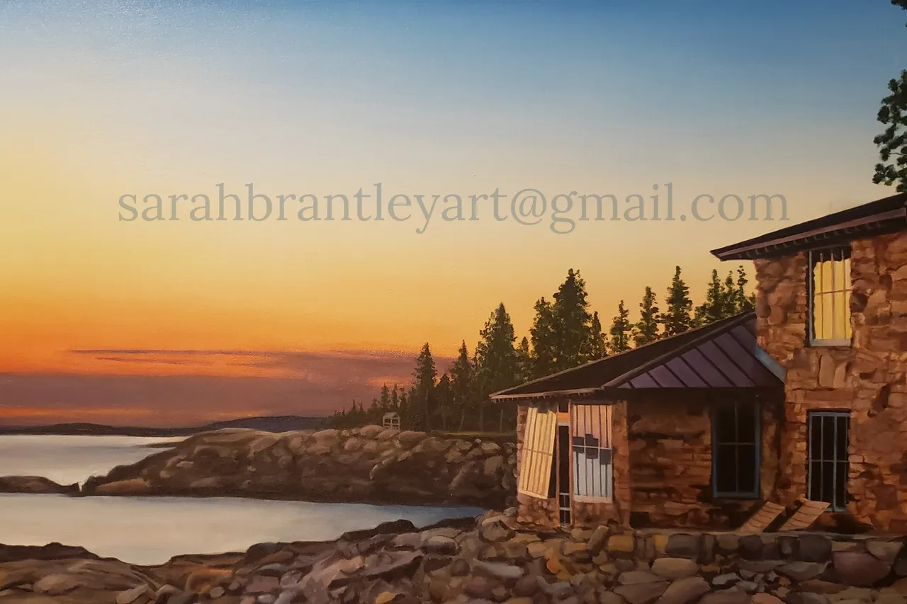 Sunset over a rocky lakeside with a stone house, trees, and a boat in the distance.