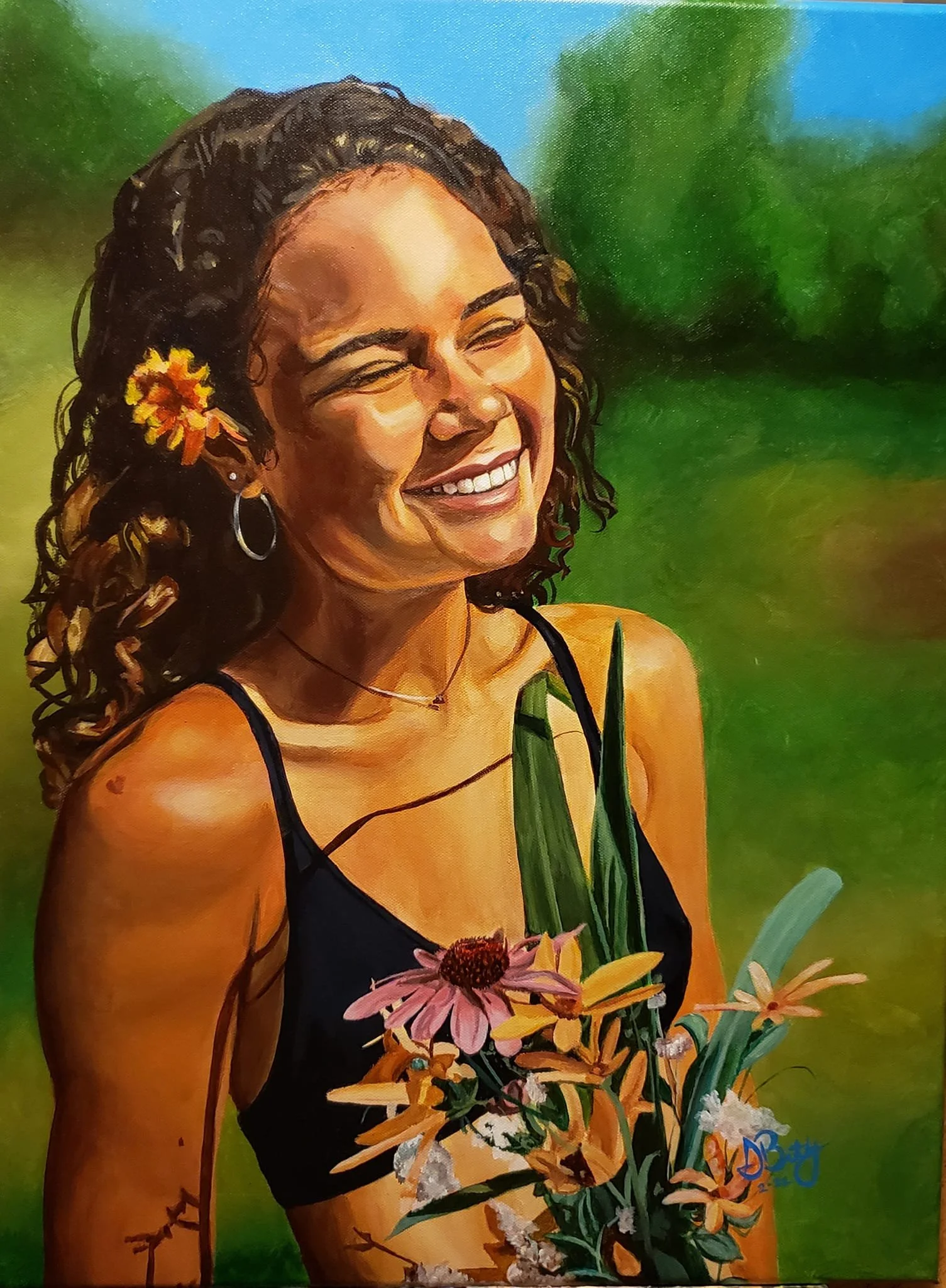 A woman with curly hair and a flower in her hair, smiling outdoors with green foliage and a blue sky in the background, holding a bouquet of pink and yellow flowers.