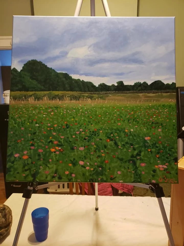 Landscape painting of a green field with flowers, trees in the background, and a partly cloudy sky.