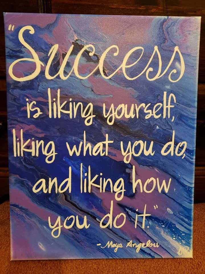 A painted canvas with a marbled background of pink, purple, and blue, featuring an inspirational quote in cream-colored text: "Success is liking yourself, liking what you do, and liking how you do it" by Moya Angelou.