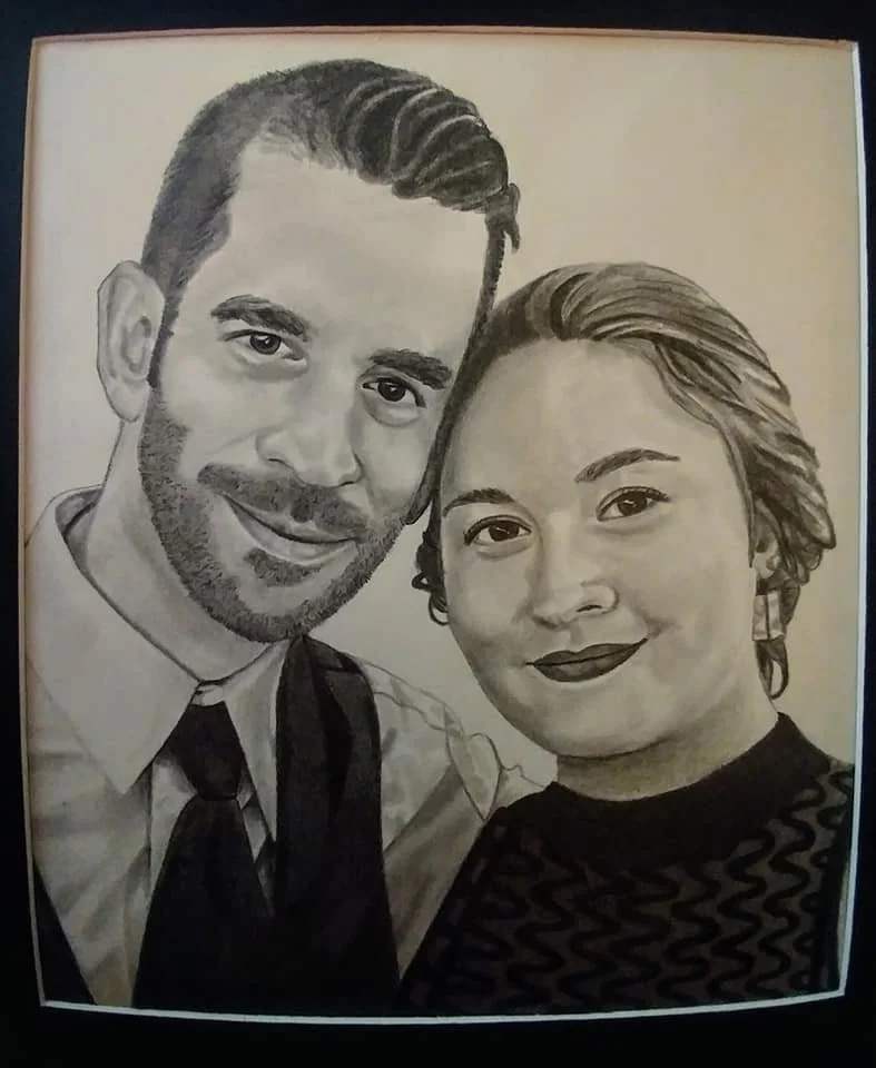 A black and white drawing of a smiling man with dark, wavy hair and a beard, and a smiling woman with short, wavy hair and dark lipstick, both facing forward.