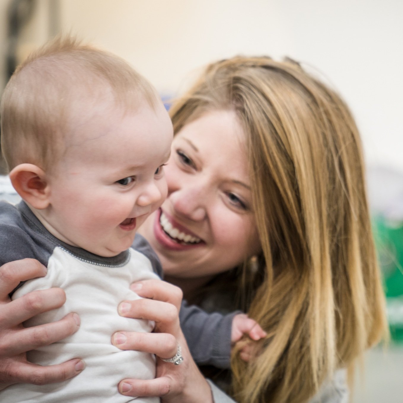 A young woman with red hair smiling and holding a happy baby with light hair in her arms.