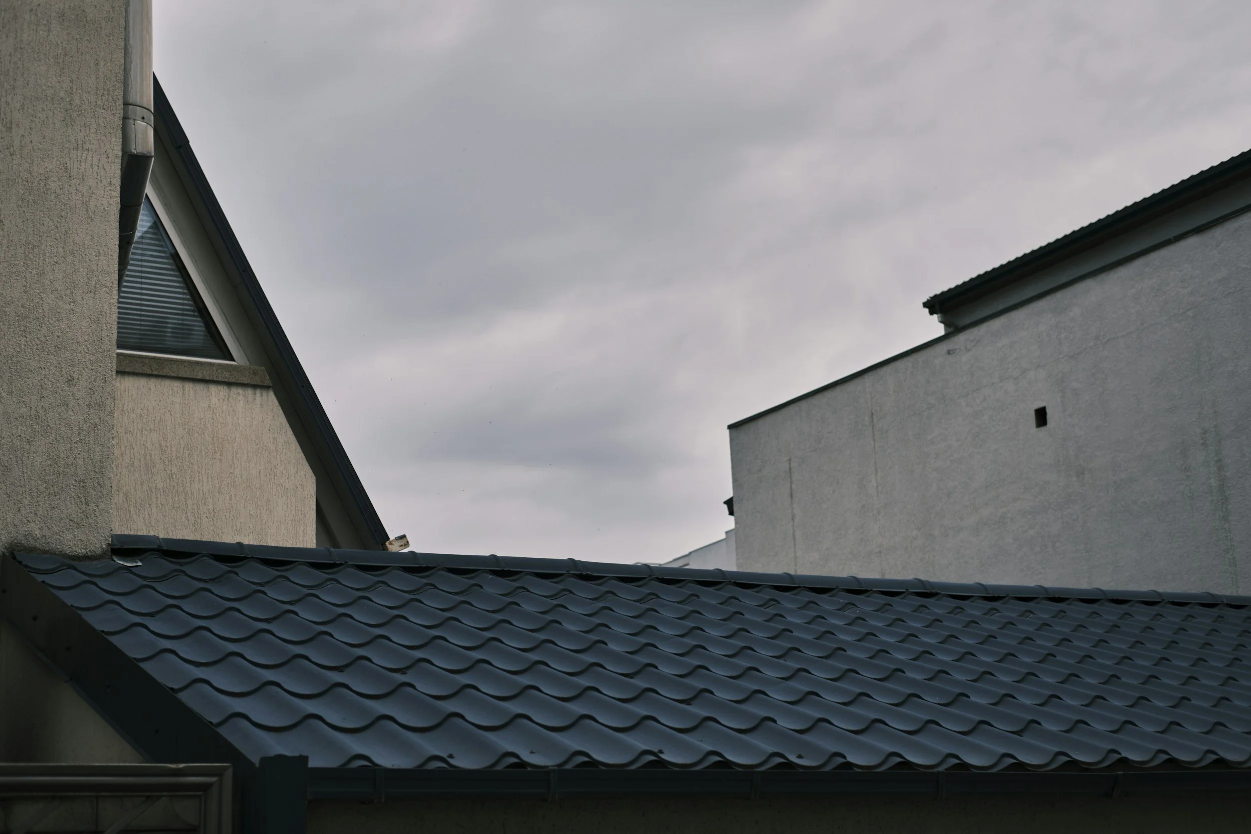 The image shows the rooftops of two houses with a cloudy sky overhead.