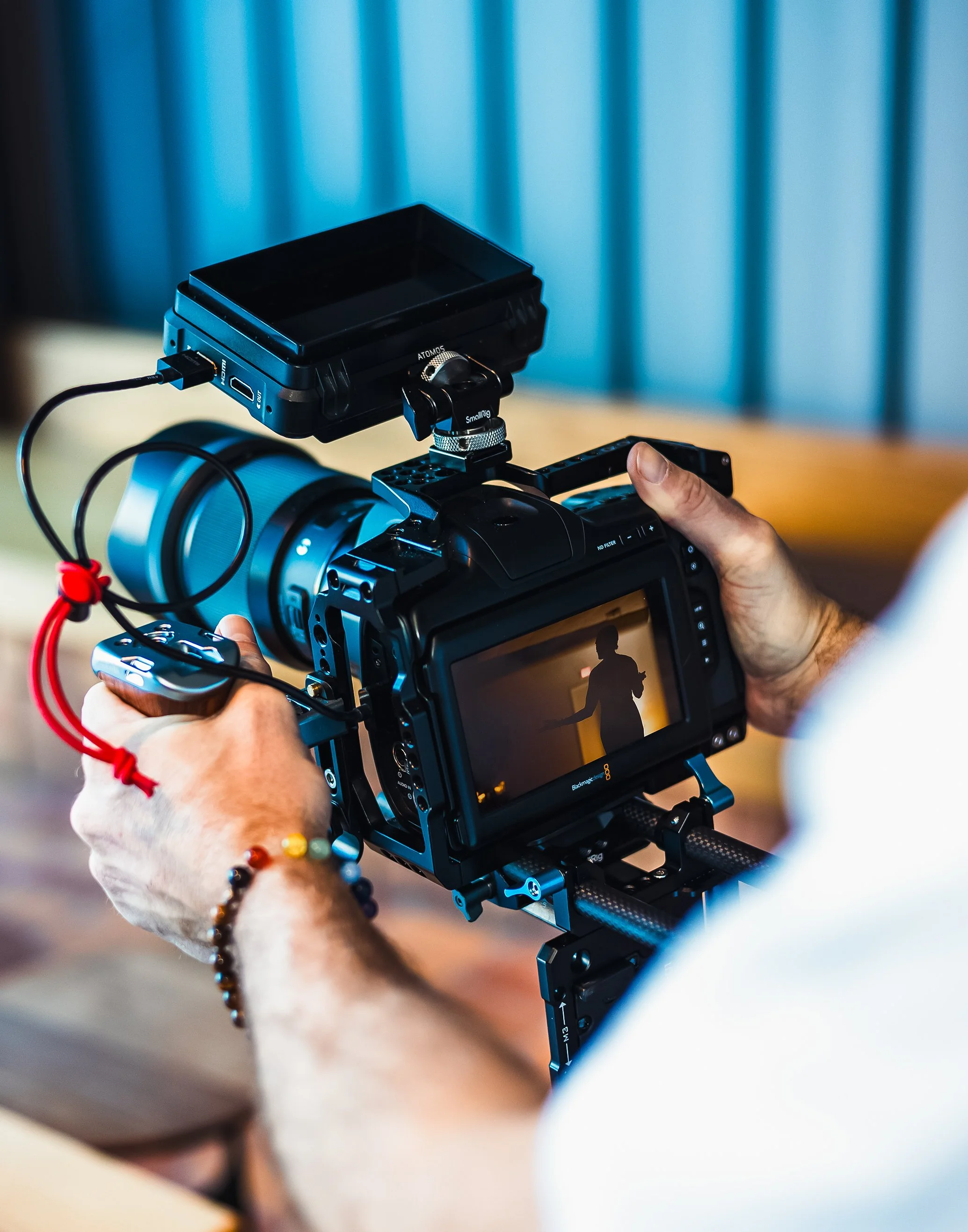 Person operating a professional video camera filming a silhouette of a woman on the screen.