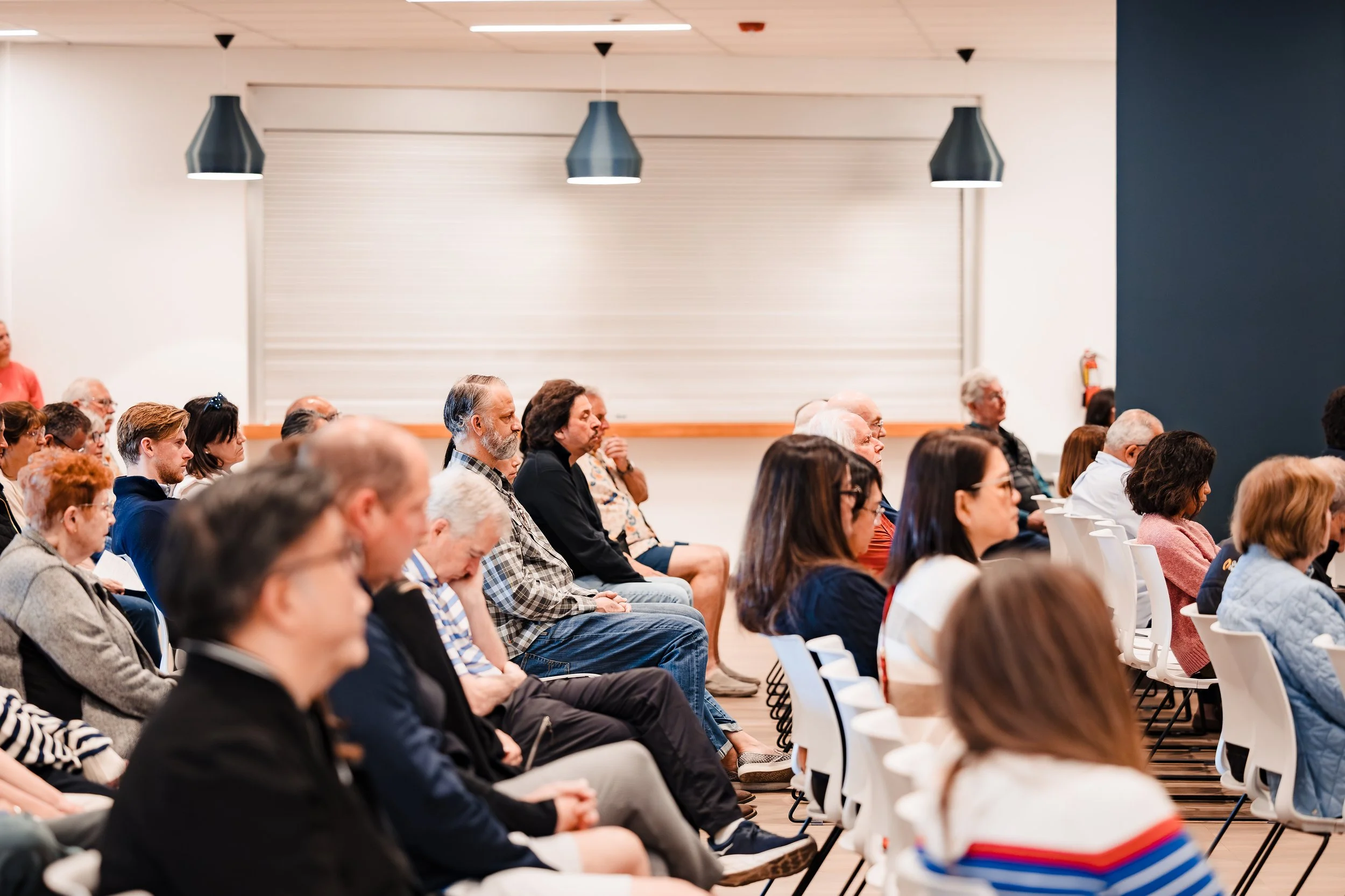 Professional corporate event photography of attendees seated and listening during an indoor business conference for company marketing and brand storytelling.