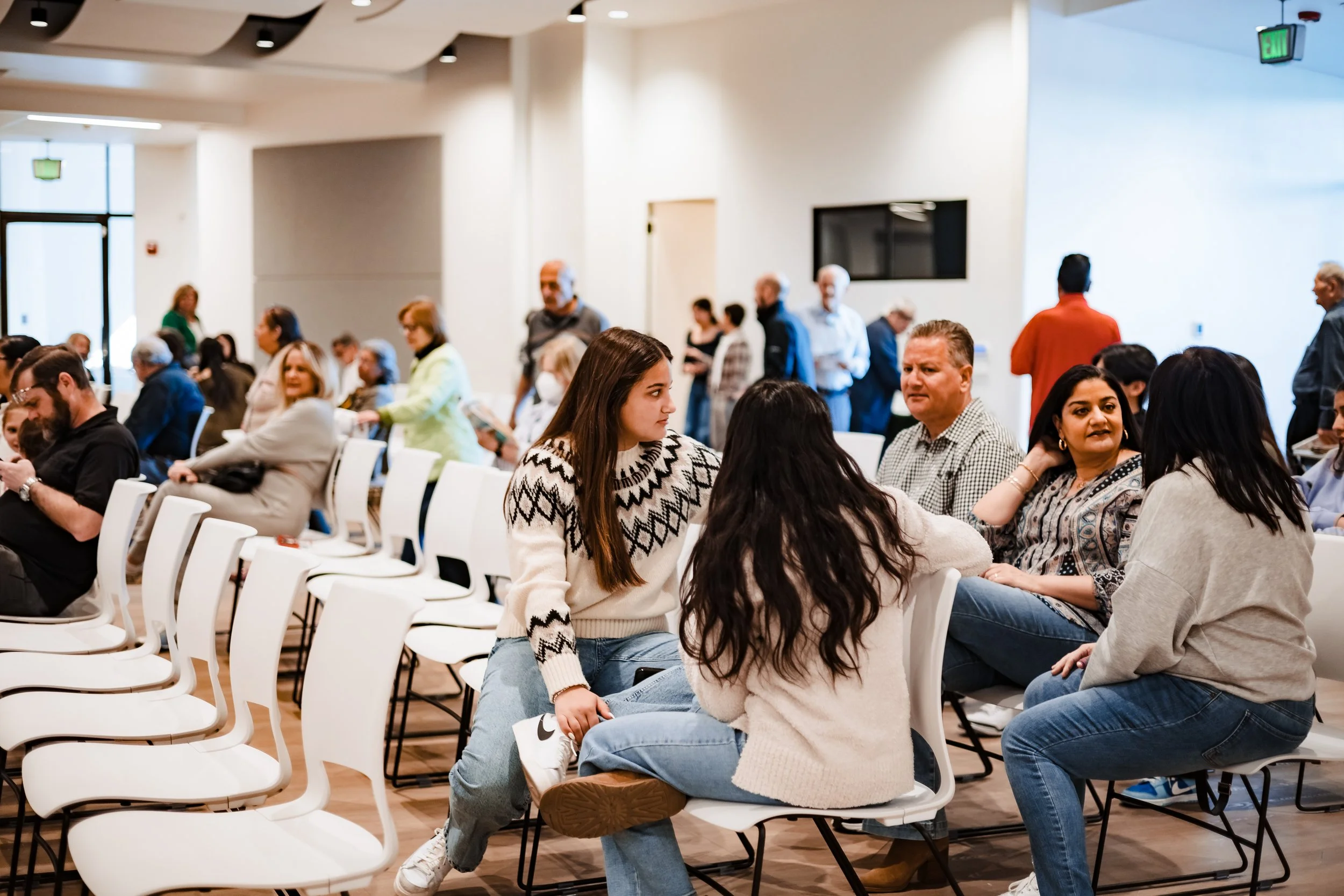 Corporate event photography of professionals networking and conversing in a bright conference or meeting space for business branding and marketing content.