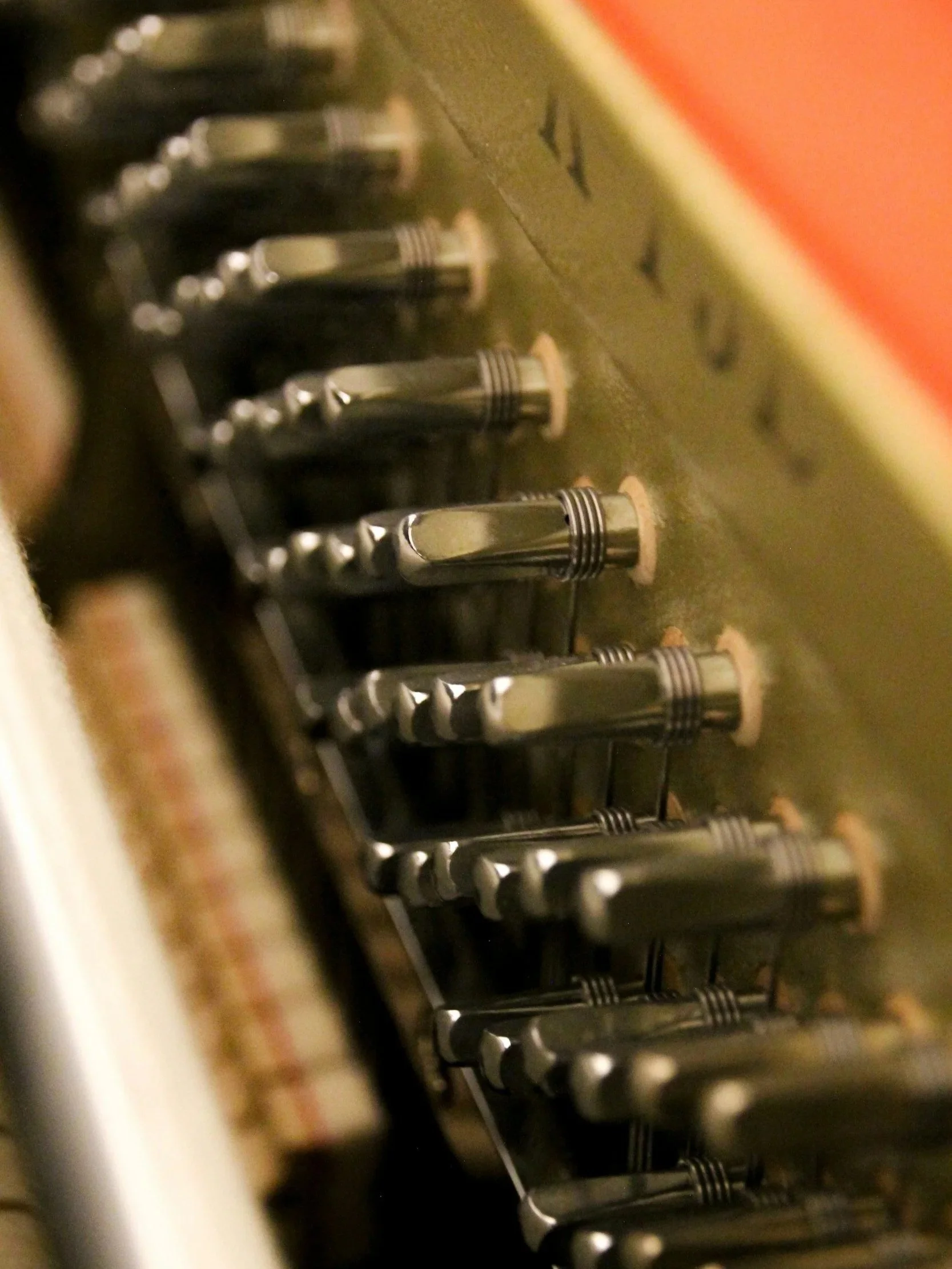 Close-up of piano tuning pins and strings inside an upright piano.