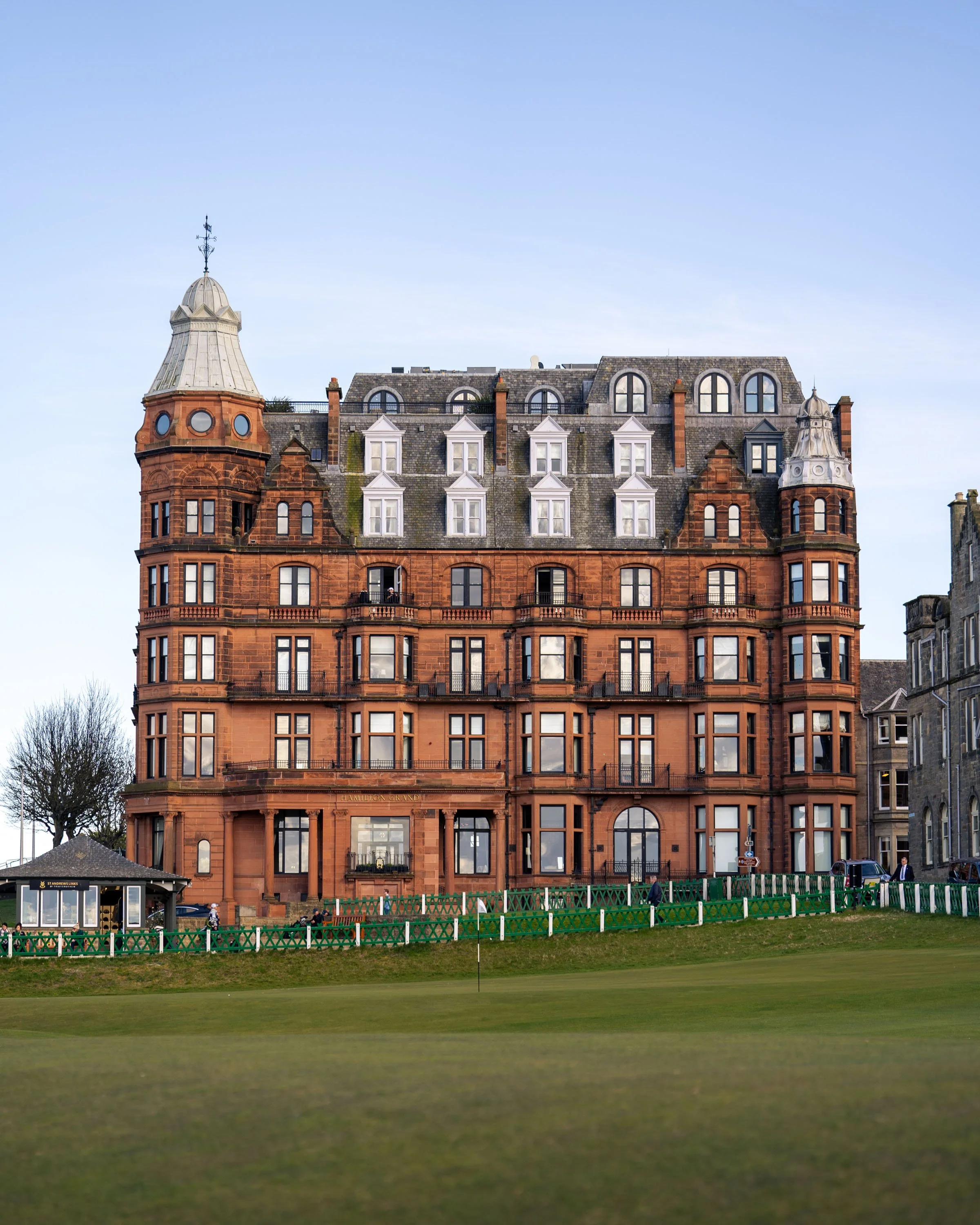 The Hamilton Grand in St. Andrews, Scotland with turreted roofs and numerous windows, situated behind the 18th green of the Old Course.