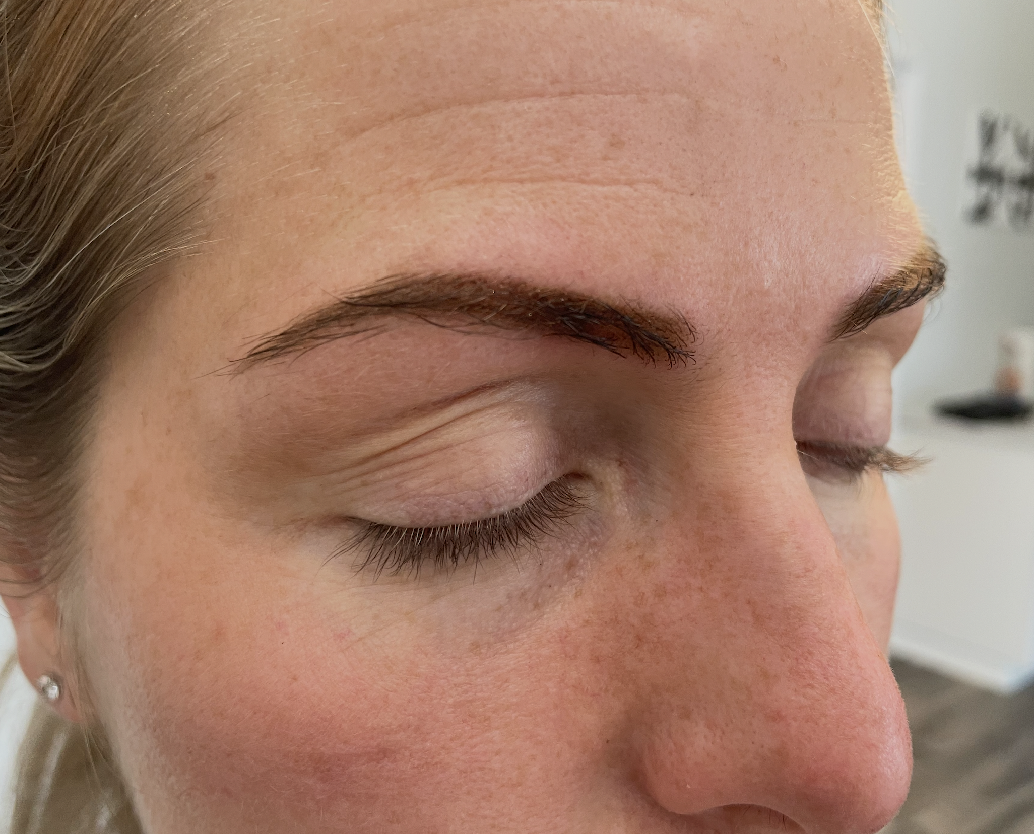 Close-up of a woman's face with well-defined eyebrows and closed eyes, showing natural skin texture.