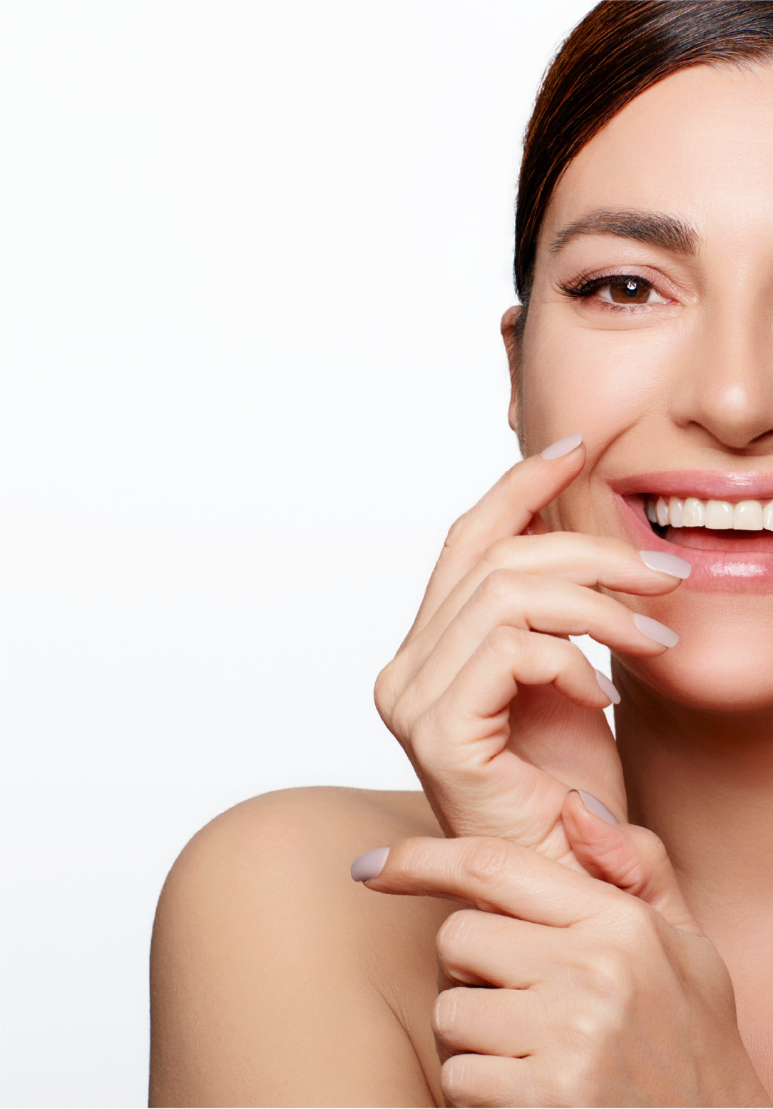 Close-up of a smiling woman touching her cheek with her finger, showing her face and shoulder against a white background.